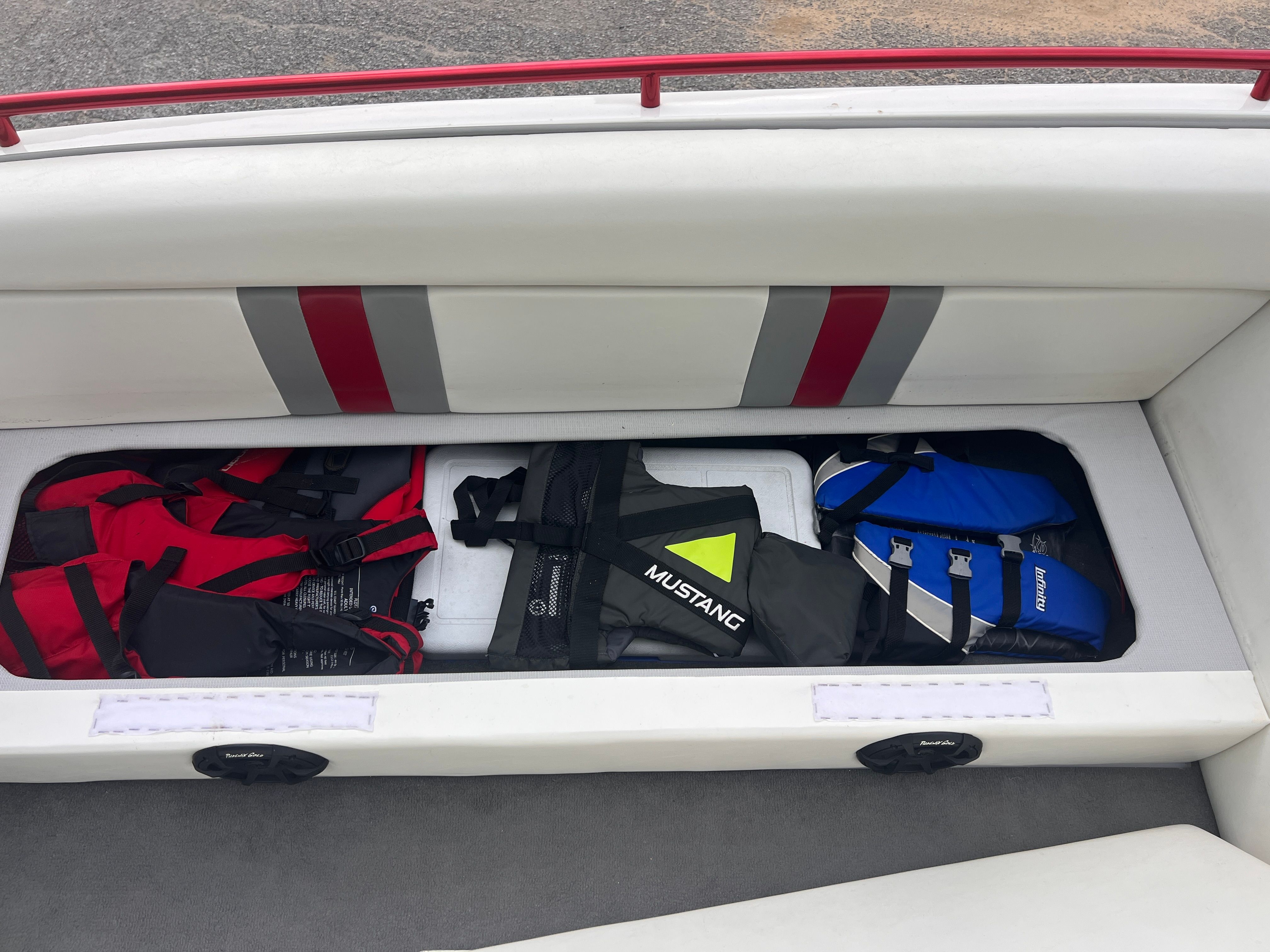 Bench seat with storage, filled with life jackets in various colors.