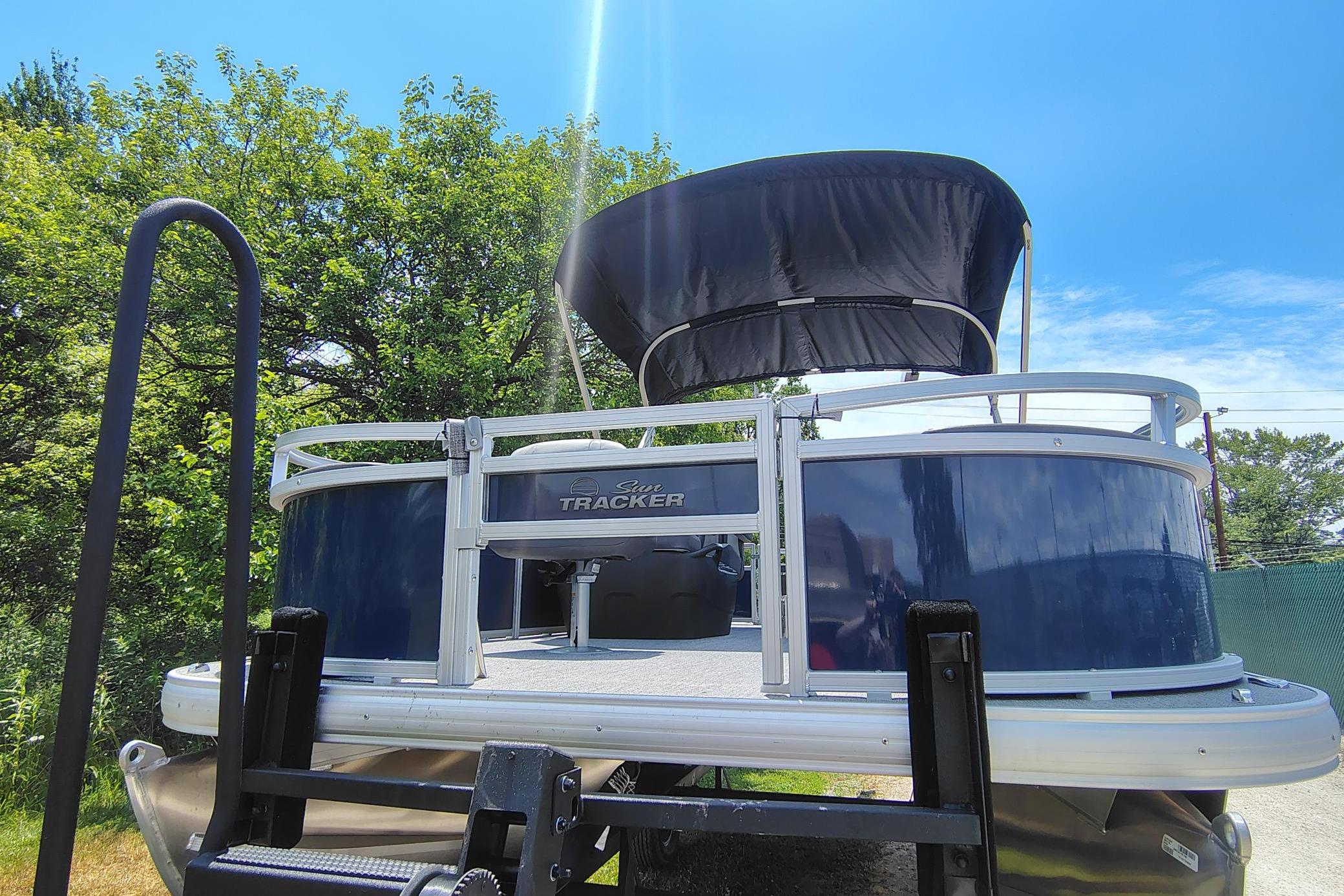 2026 Sun Tracker Bass Buggy 18 DLX pontoon boat with canopy, parked outdoors.