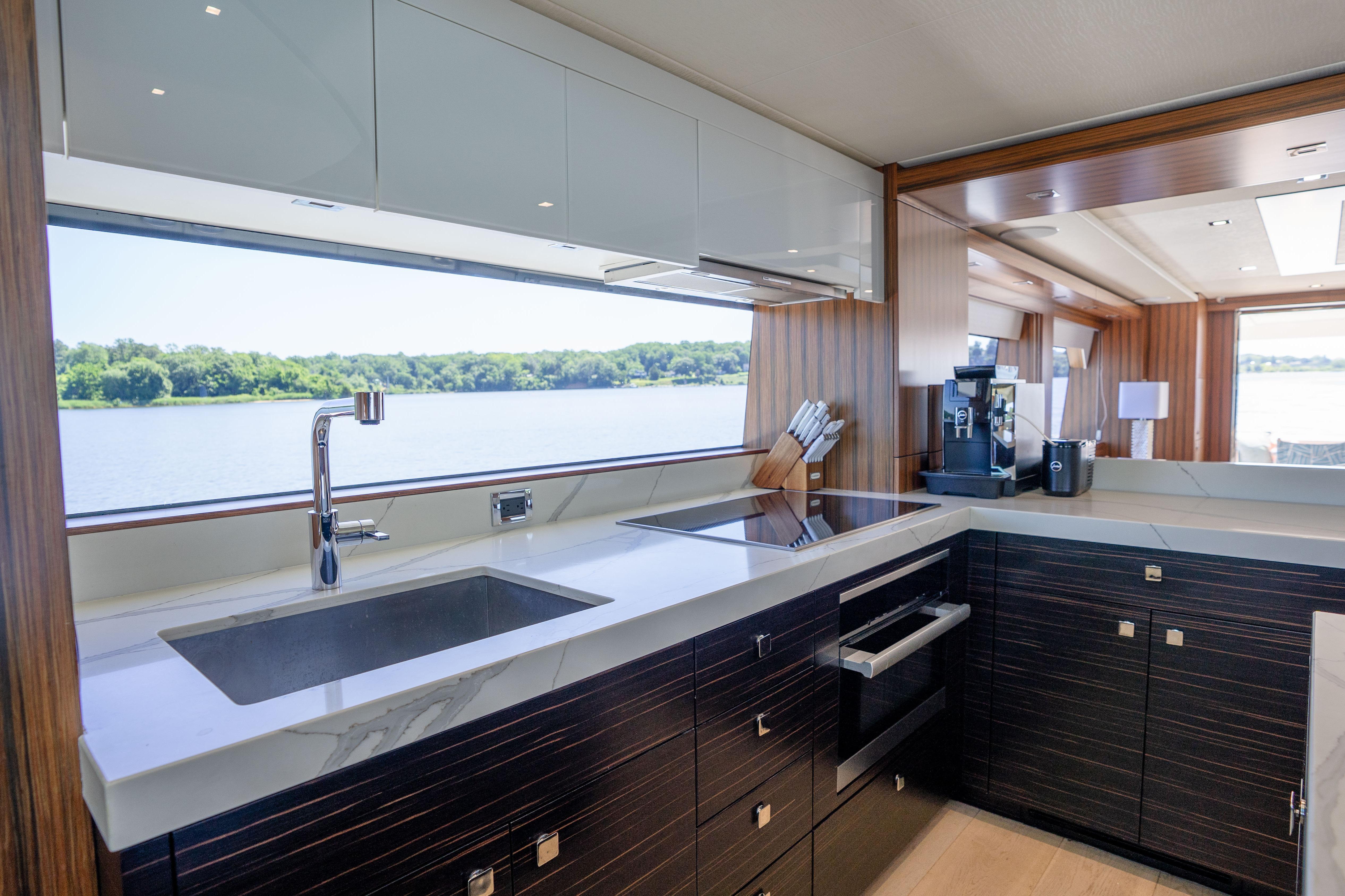 Luxurious kitchen interior of 2021 Hatteras M75 Panacera yacht with scenic water view.