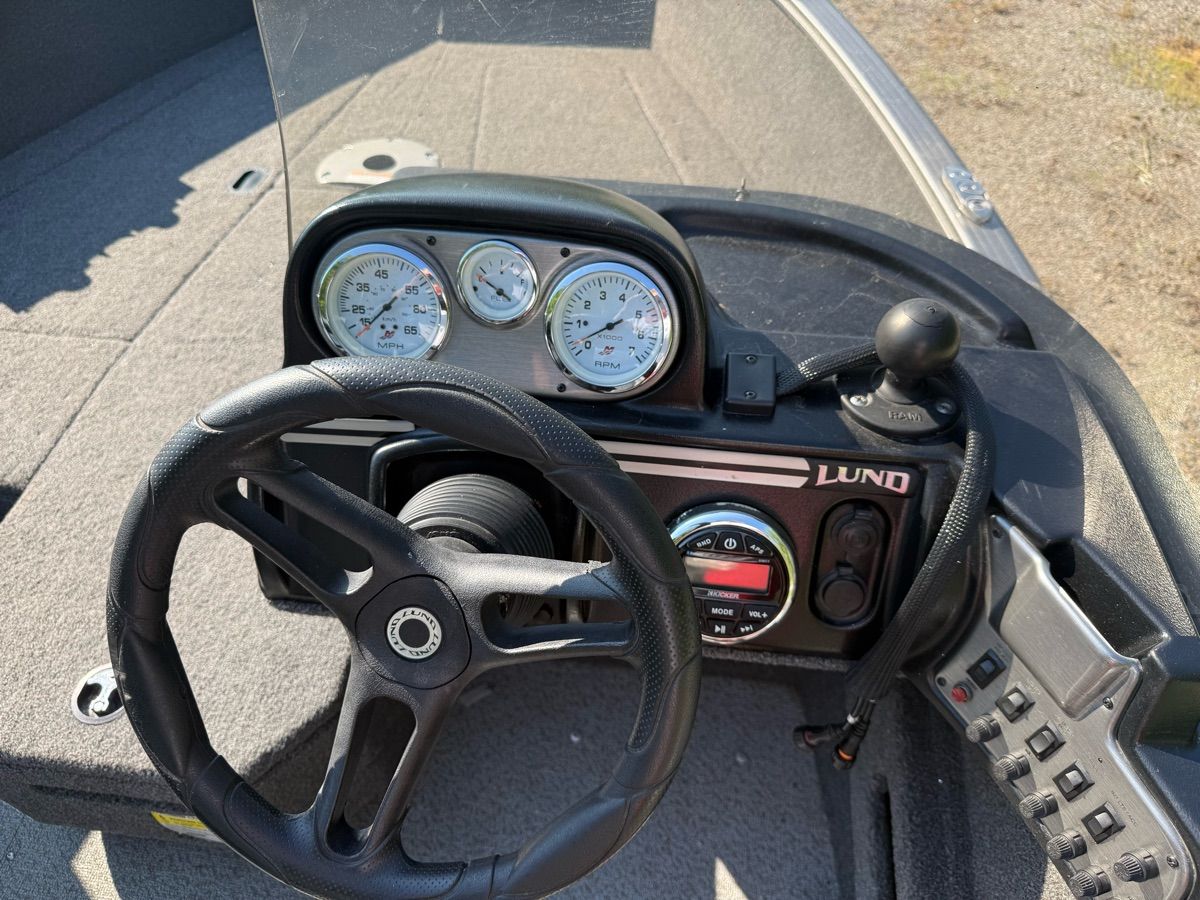 The image shows the cockpit of a 2019 Lund 1775 Adventure SS boat with steering wheel and gauges.