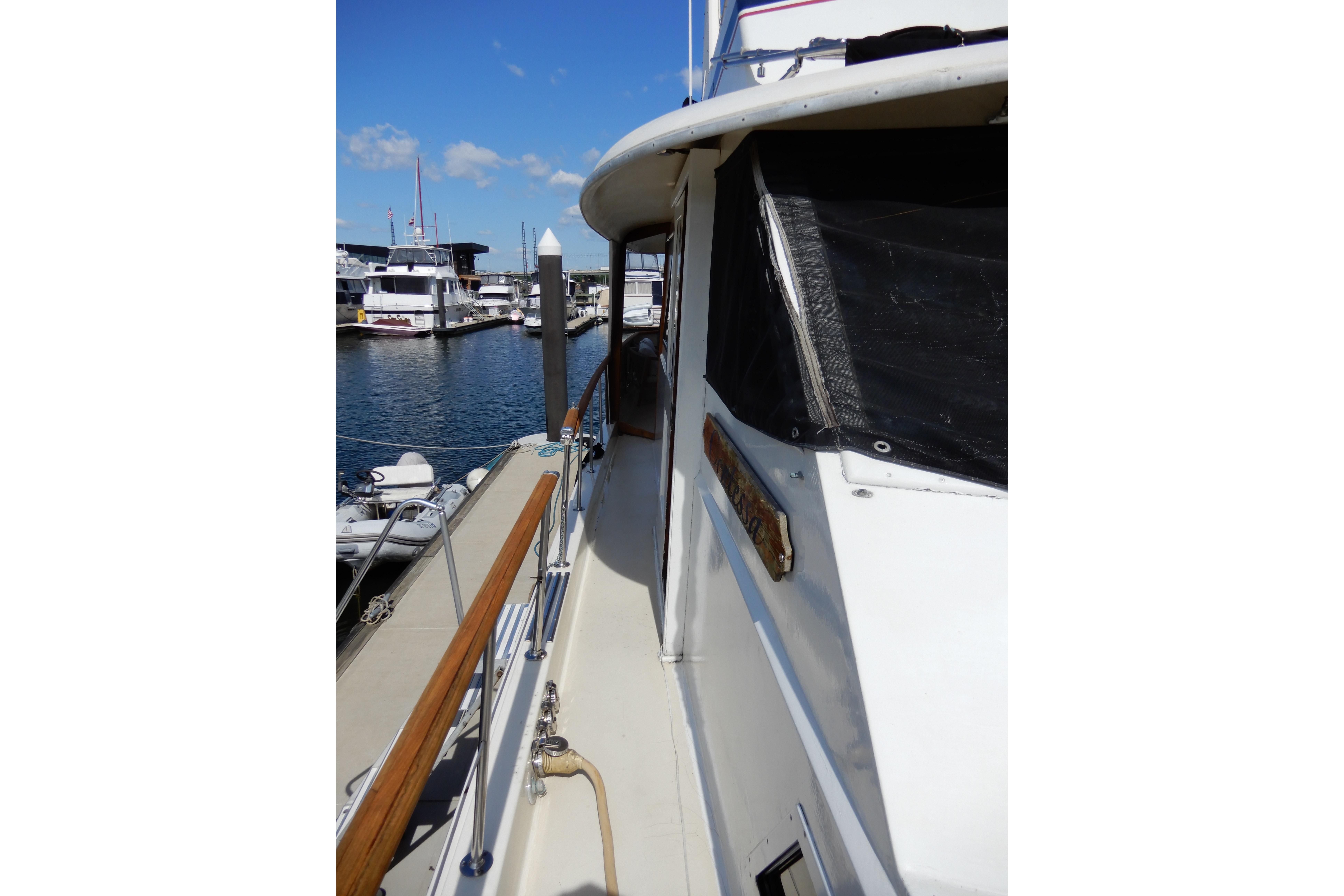 1974 Hatteras 53 Motor Yacht docked, showcasing side deck and marina view.