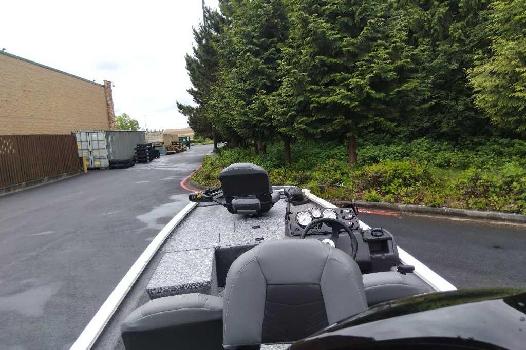 2026 Tracker Pro 170 boat parked near trees and industrial area.
