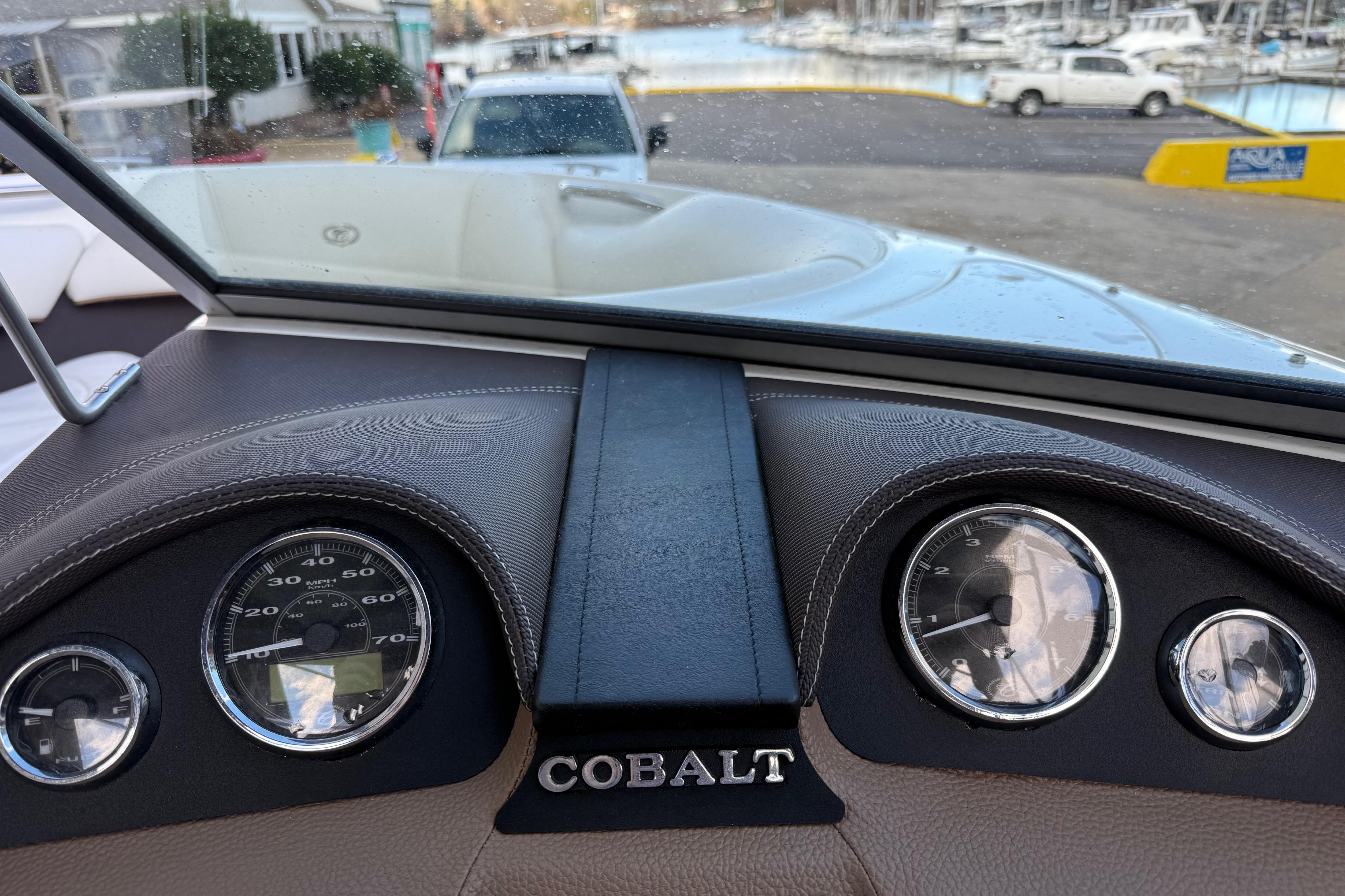 Dashboard of a 2015 Cobalt 200 boat with gauges and marina view.