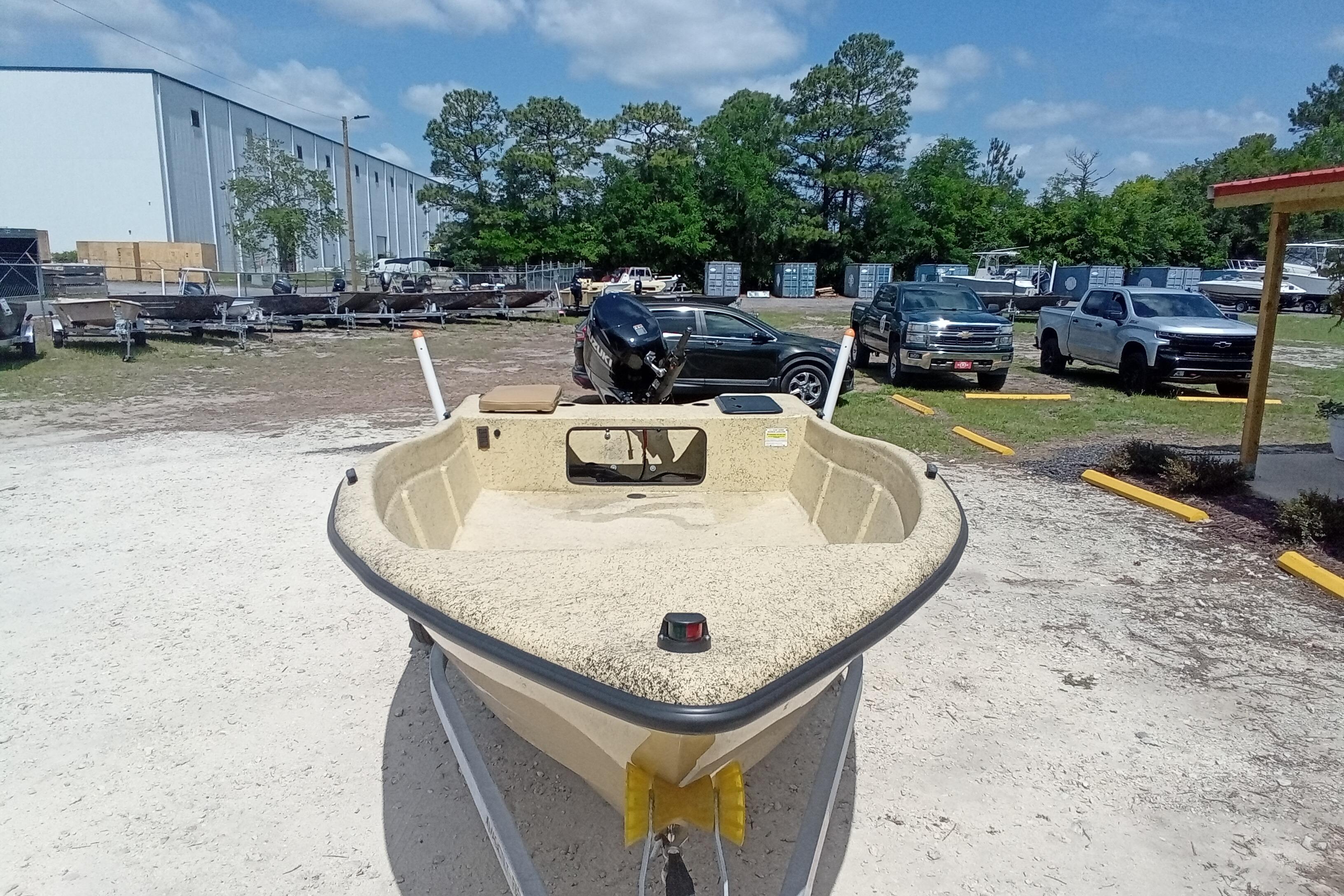 2025 Fibercraft F16 boat on trailer in outdoor lot with trucks and trees.