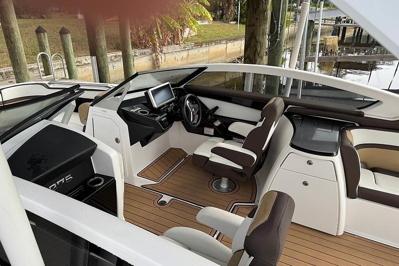 2023 Yamaha 275SDX boat interior with modern dashboard and seating, docked by a wooden pier.