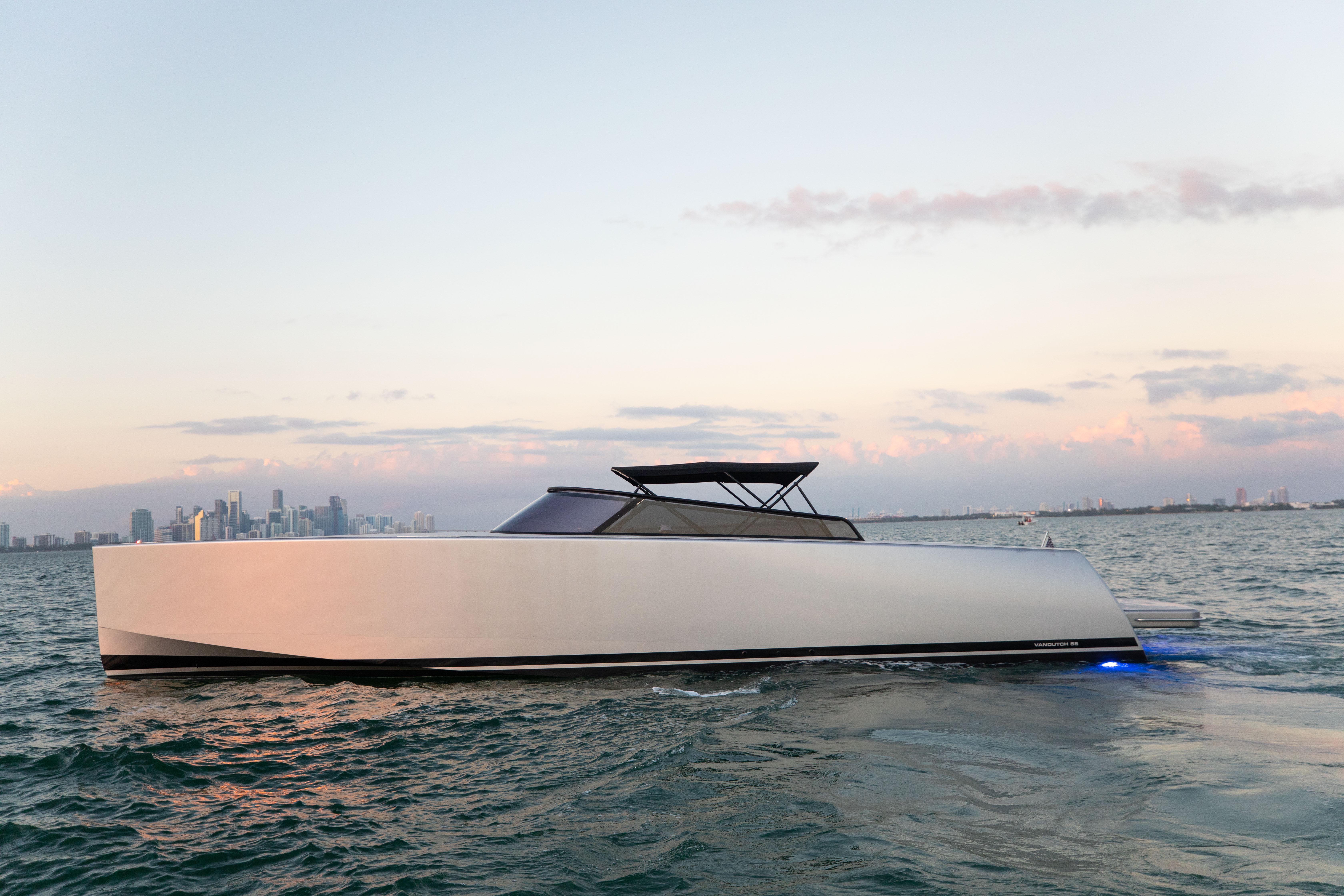 VanDutch 55 yacht cruising on water at sunset, city skyline in background, 2017 model.