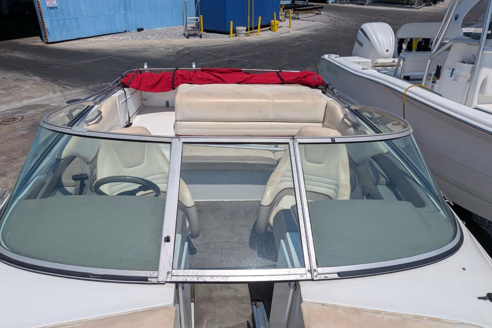 2020 Cobalt 206 boat with beige interior and red cover, docked near blue building.