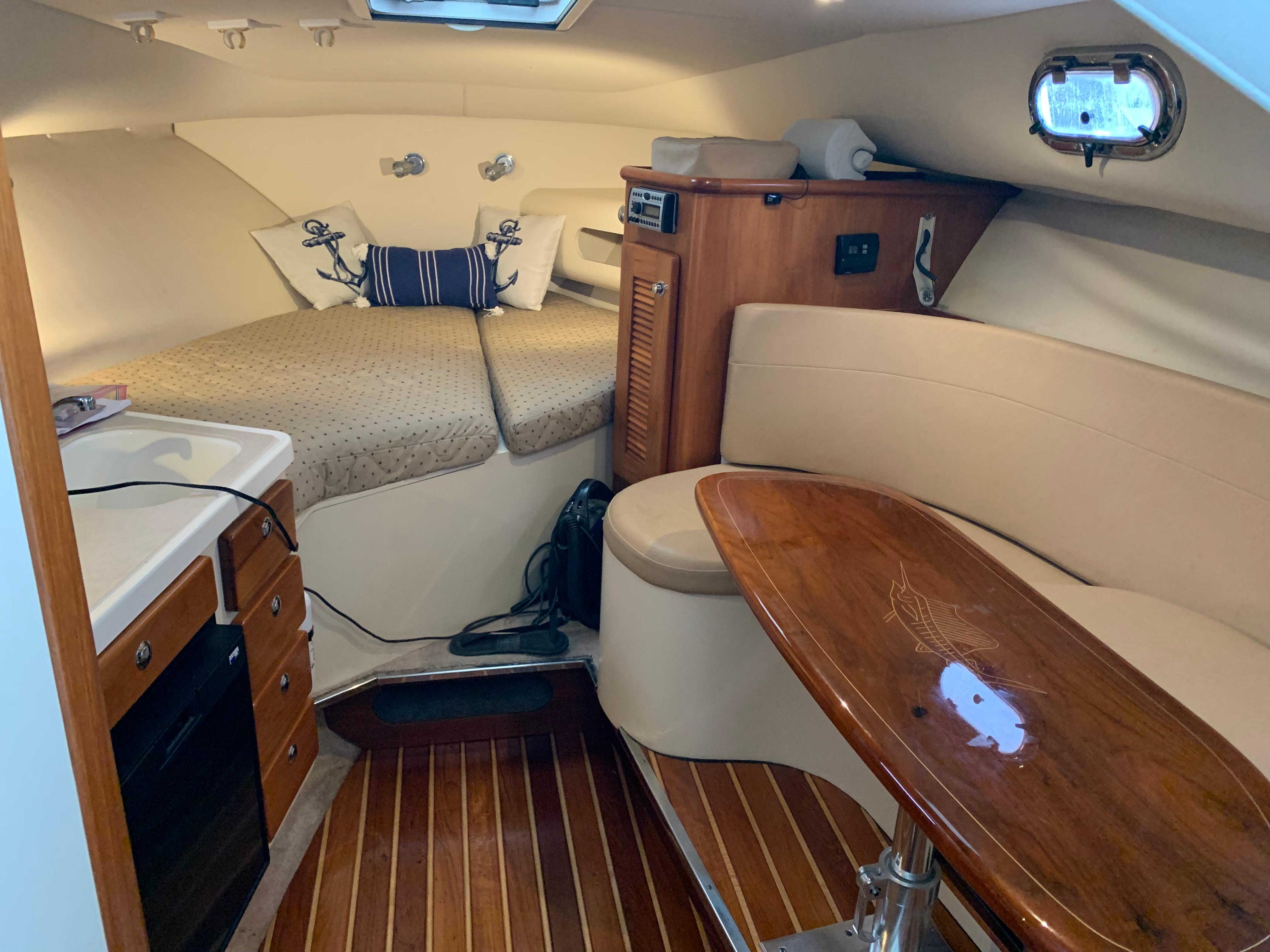 2007 Pursuit OS 335 cabin interior with cozy seating, wooden table, and compact kitchen area.