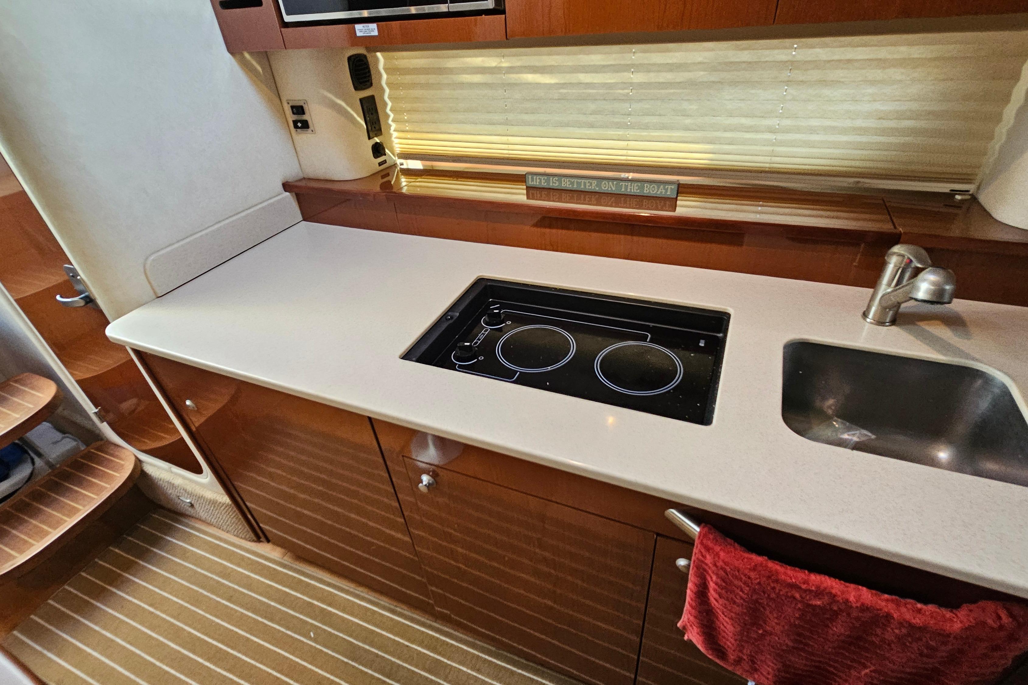Interior of 2008 Sea Ray Sundancer 350 yacht kitchen with stove and sink.