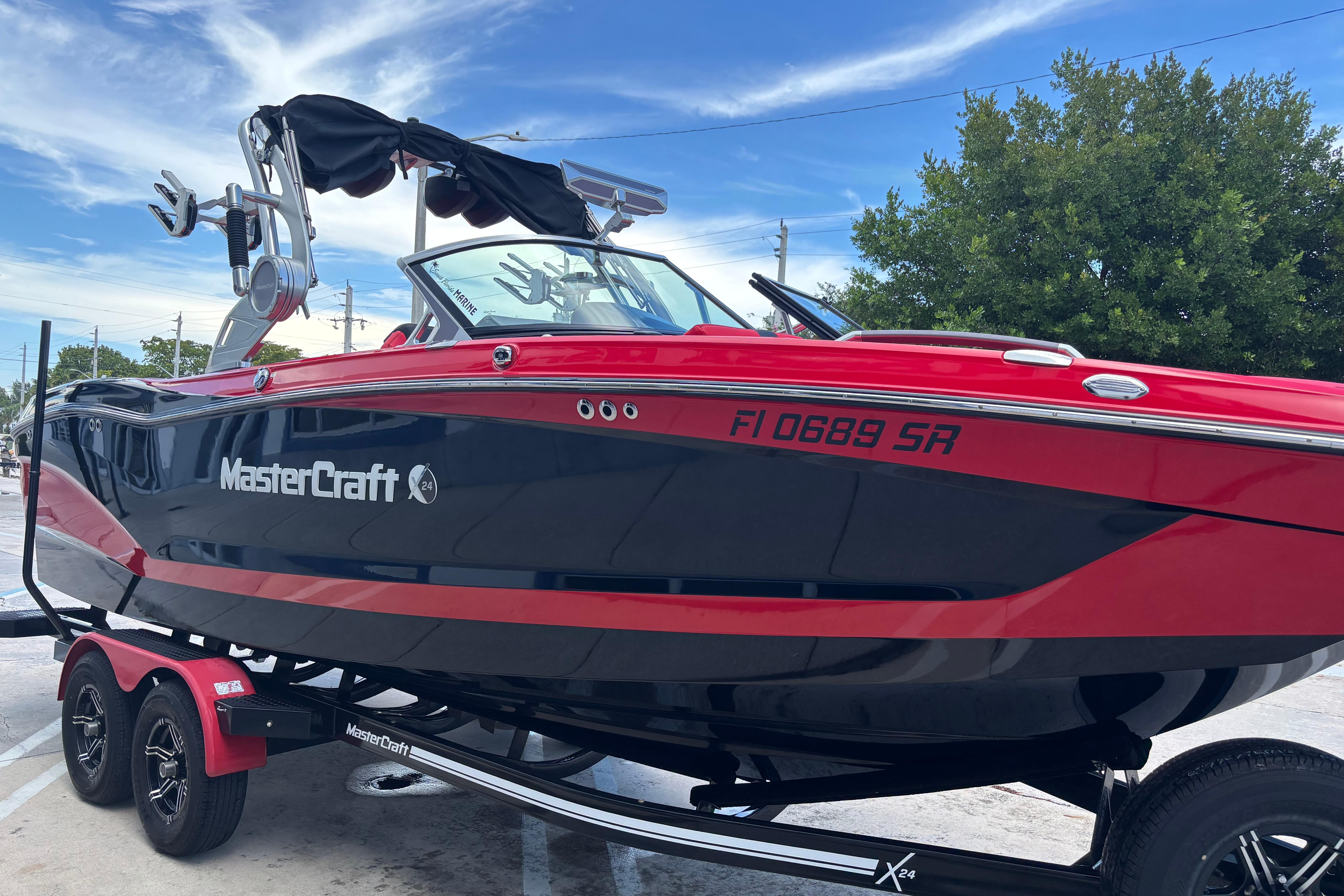2020 MasterCraft X24 boat in red and black on a trailer, parked outdoors.