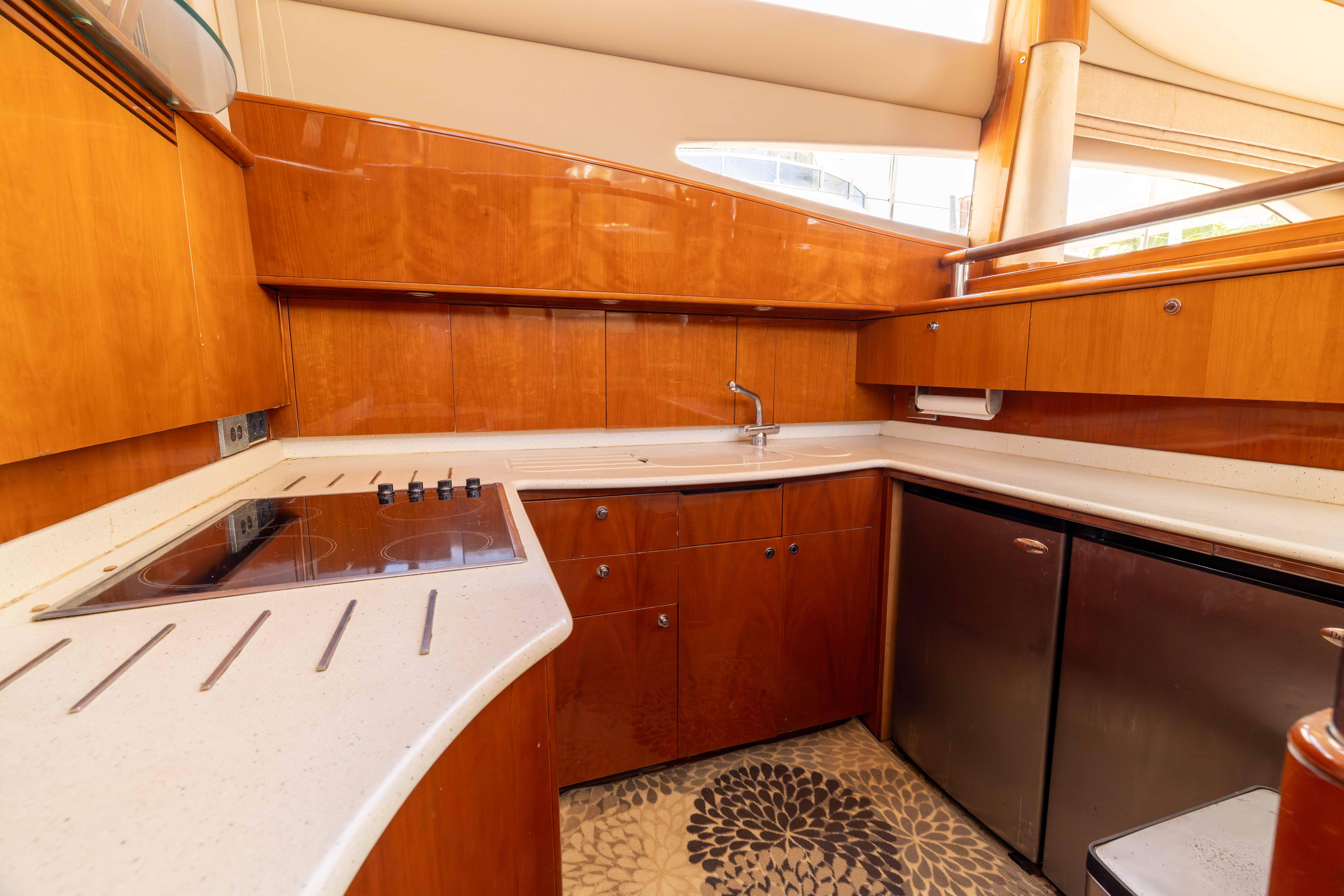 Luxurious yacht kitchen with wooden cabinetry, modern appliances, and sleek countertops on a 2002 Princess 61.
