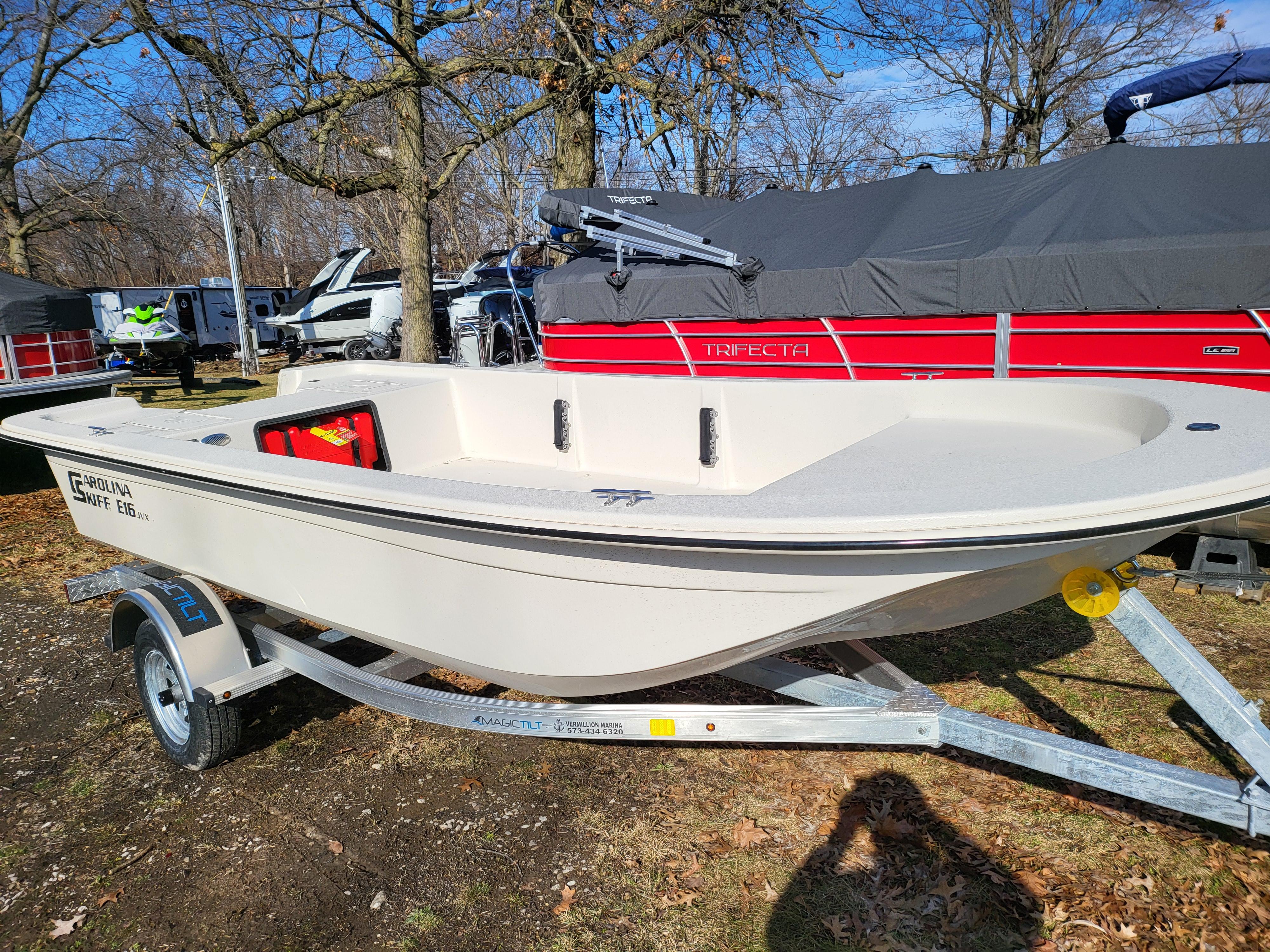 2024 Carolina Skiff E16 JVX TH boat on a trailer in a wooded area.