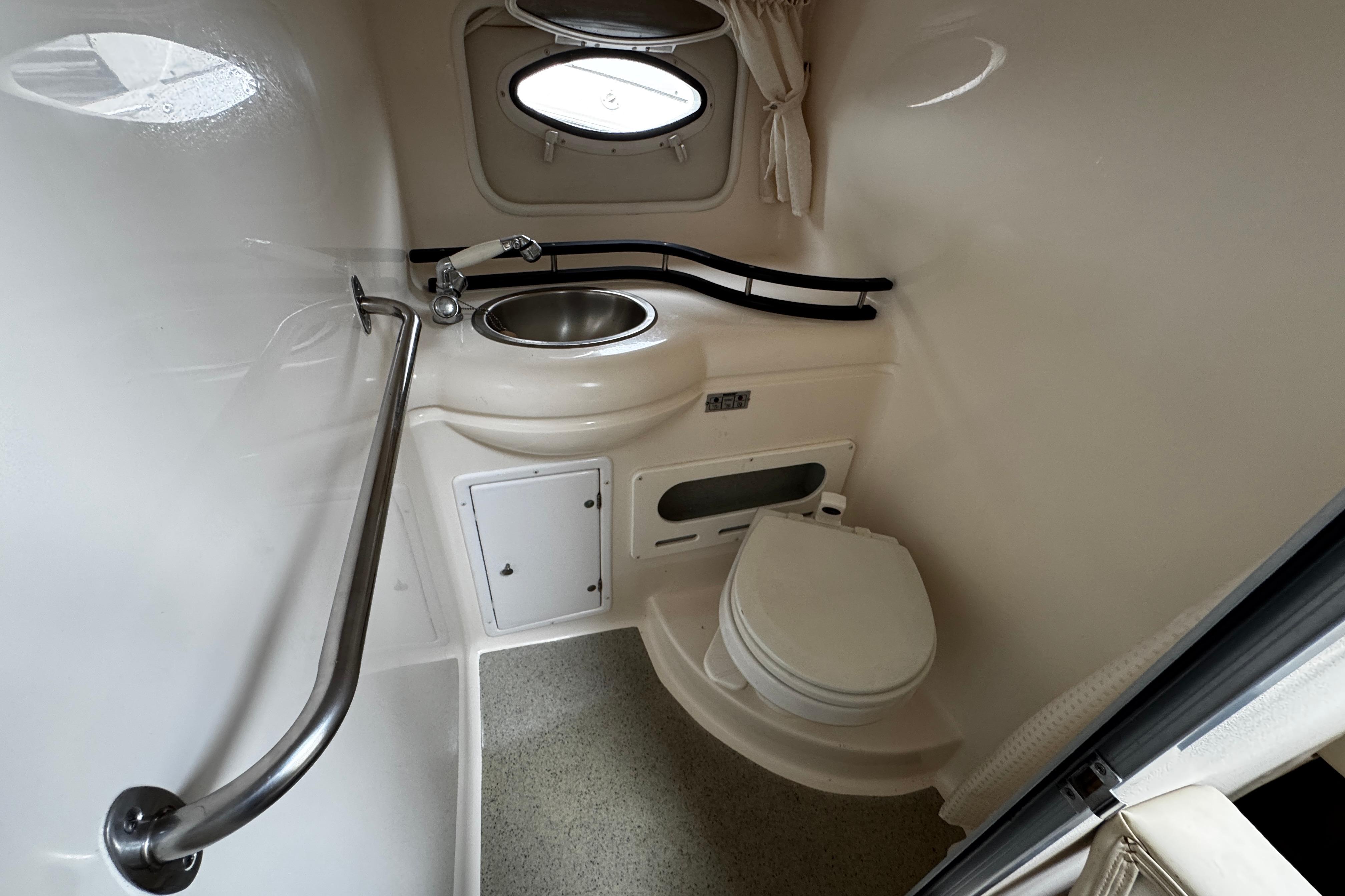 2007 Rinker 300 Fiesta Vee boat bathroom with sink, toilet, and porthole window.