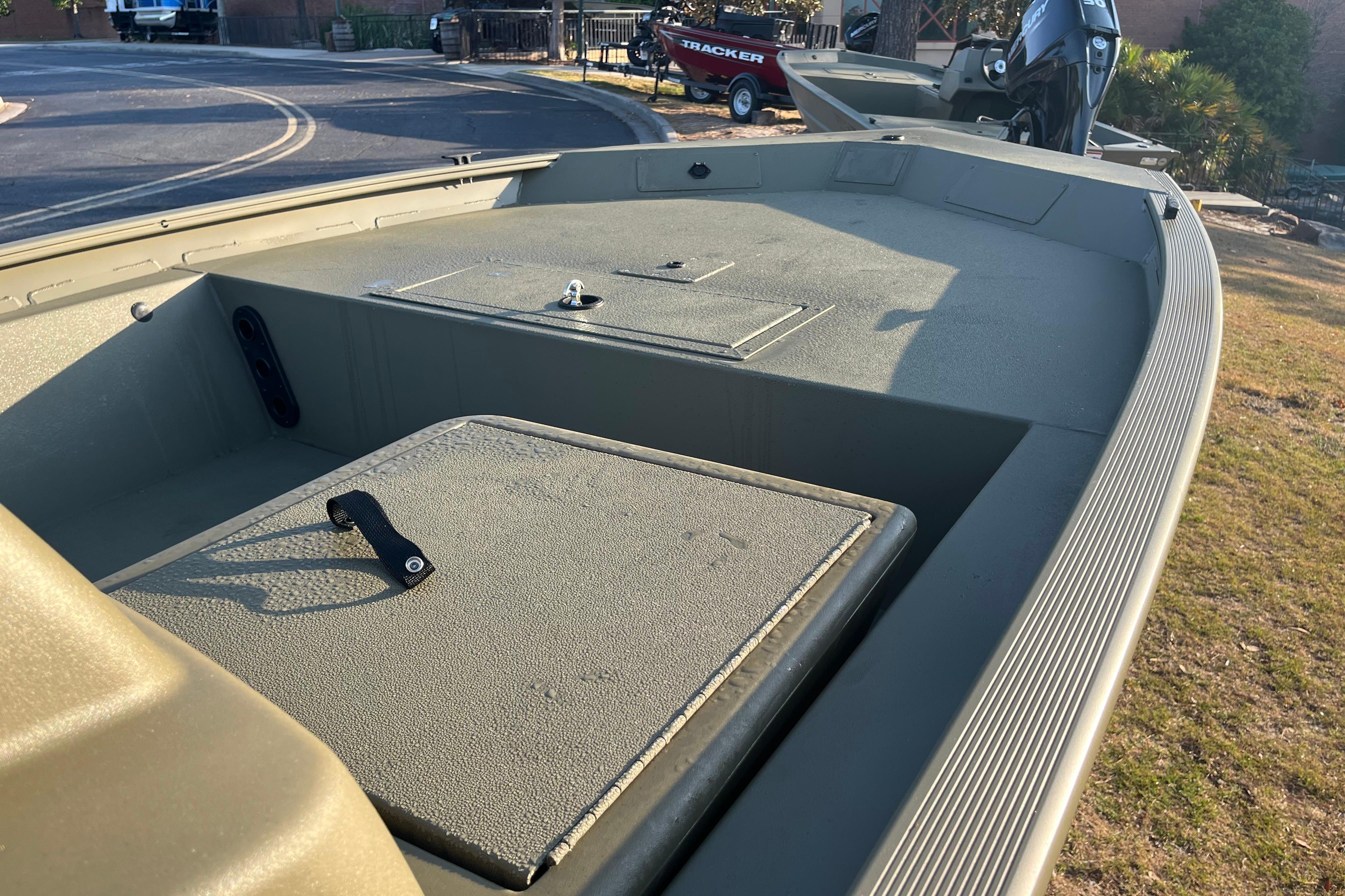 2026 Tracker Grizzly 1754 SC boat interior with storage compartments and motor, parked outdoors.