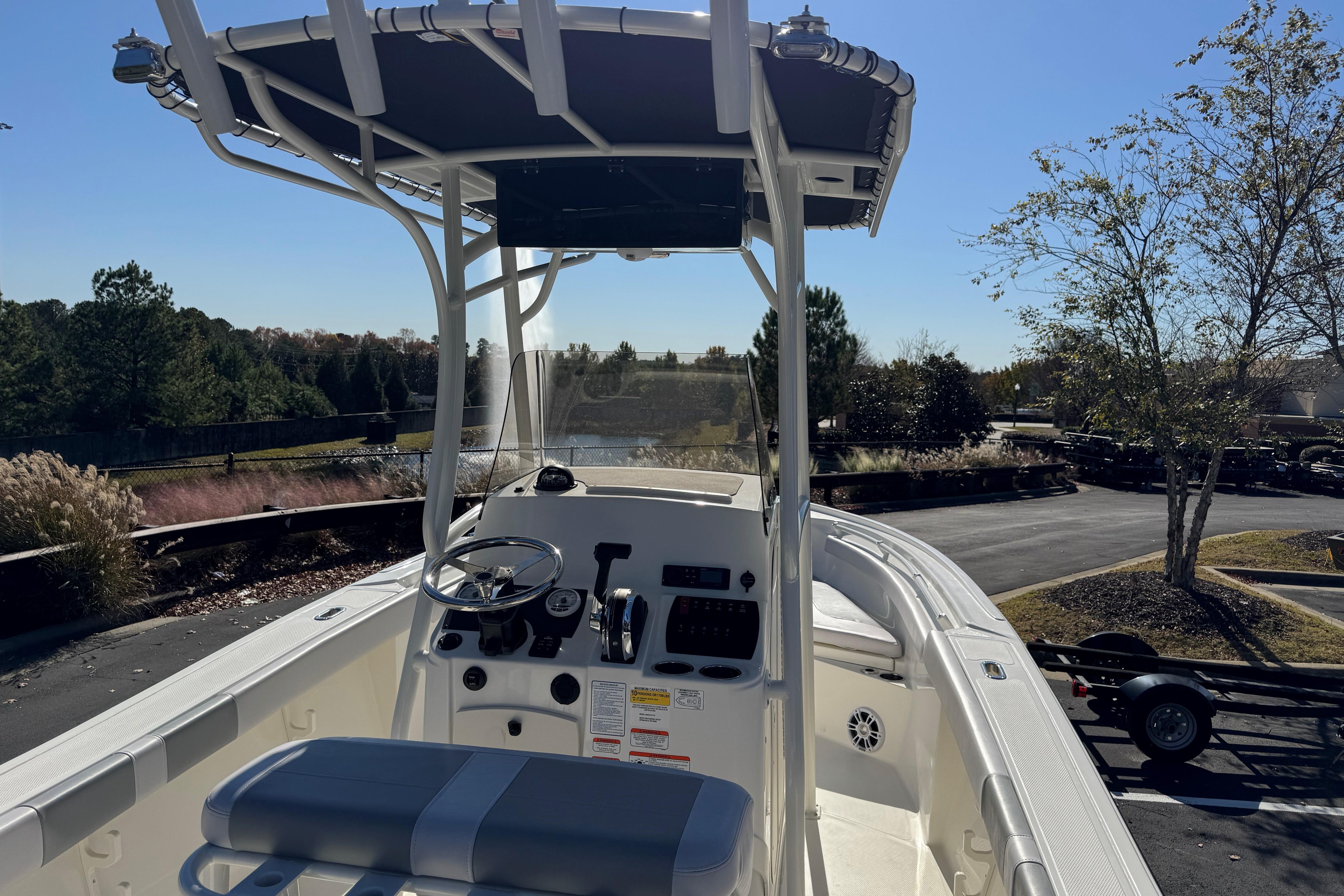 2026 Mako 214 Center Console boat with T-top, parked outdoors on a sunny day.