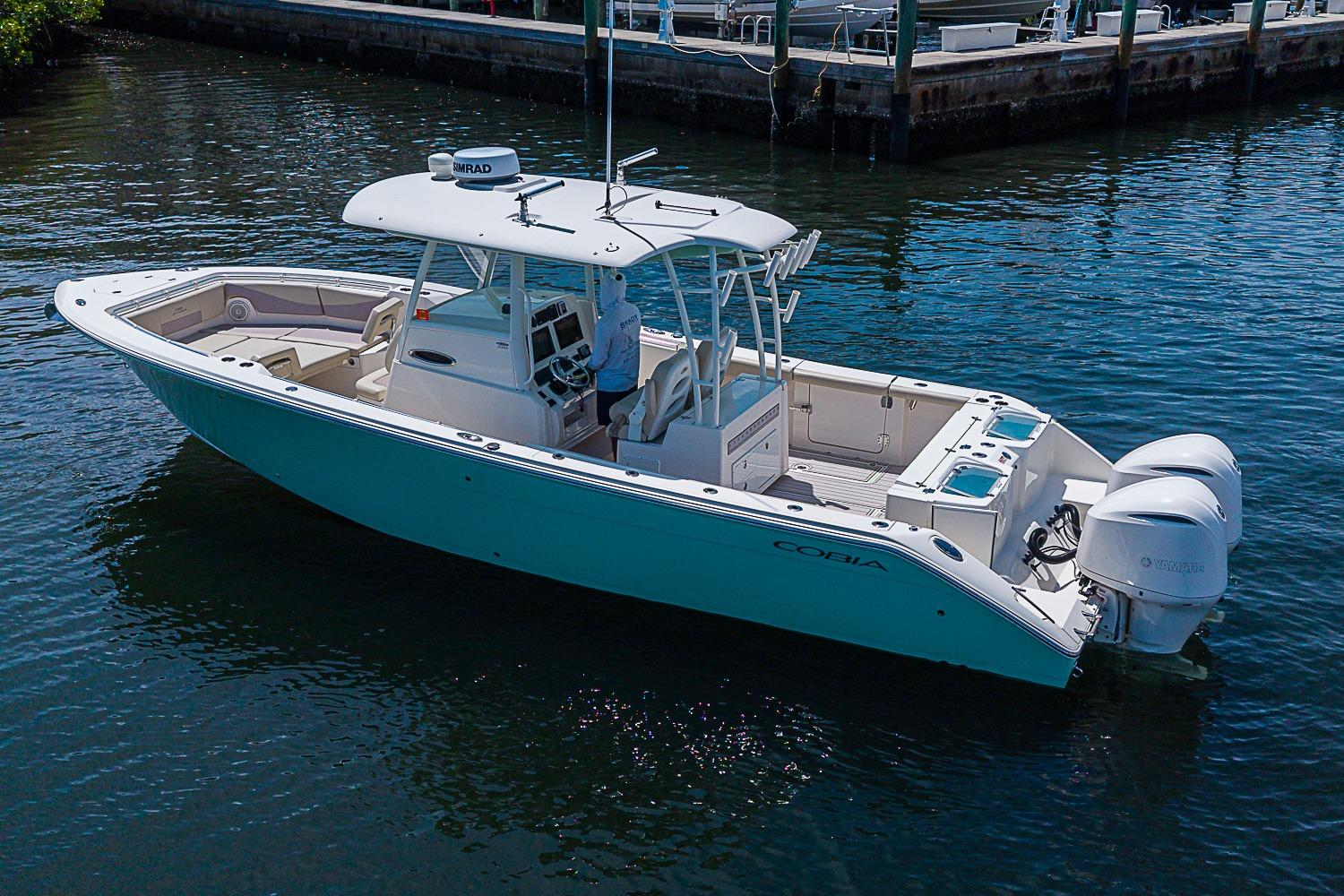 2019 Cobia 320 Center Console boat on calm water, featuring dual outboard engines.