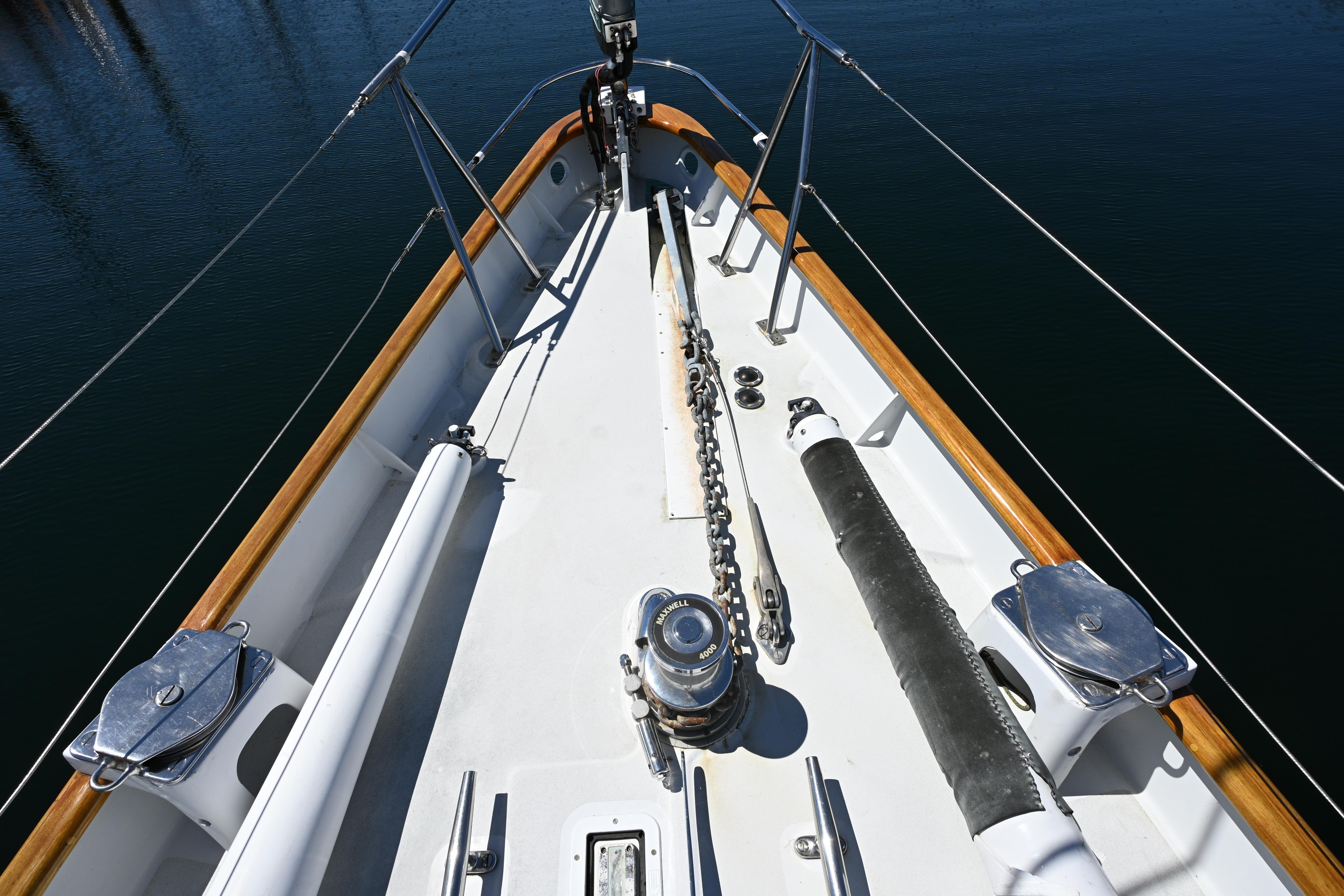 Bow of 1968 Abeking & Rasmussen Tripp 74 yacht with anchor chain and wooden railings.