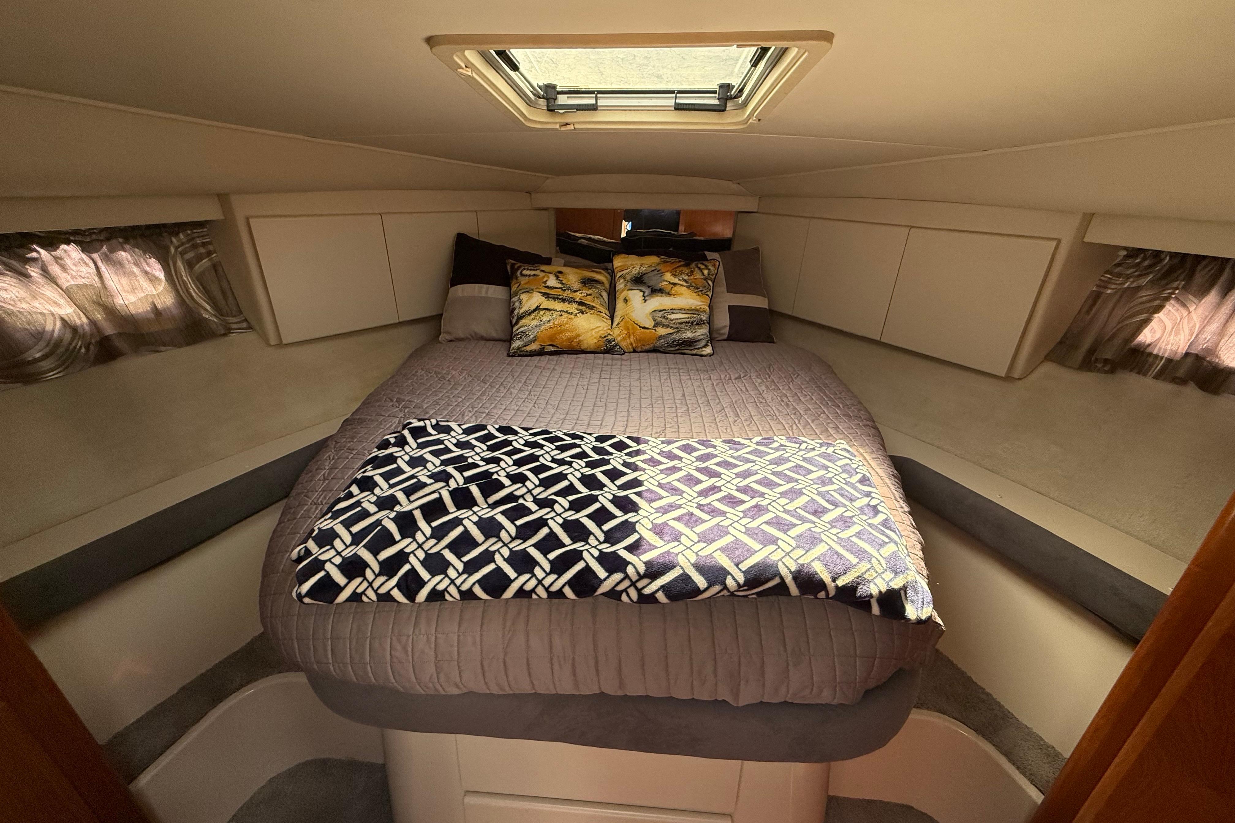 Cozy bedroom interior of 1995 Carver 370 Voyager yacht with skylight and decorative pillows.