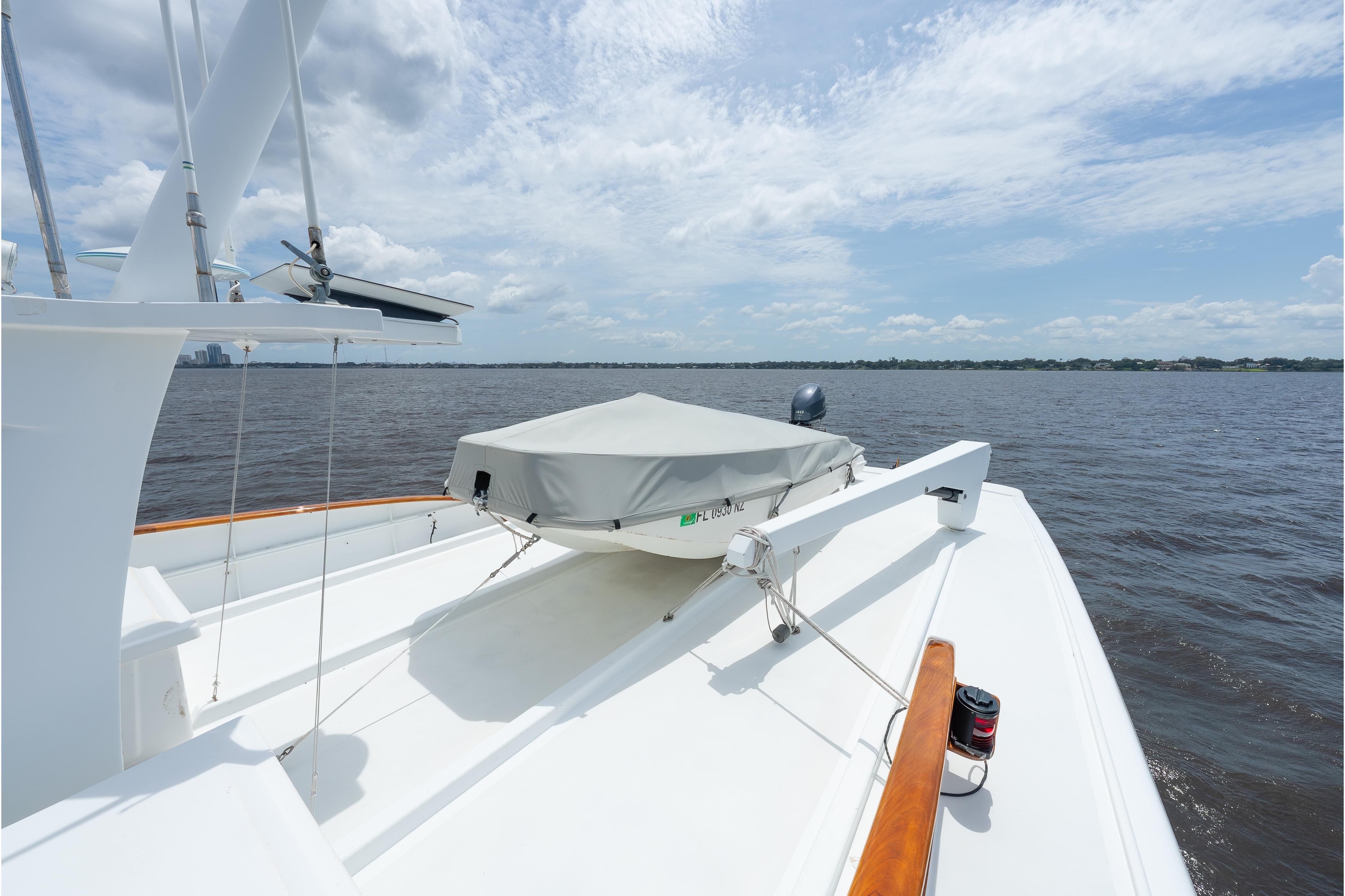 1963 Trumpy Classic yacht deck with covered boat, overlooking calm waters.