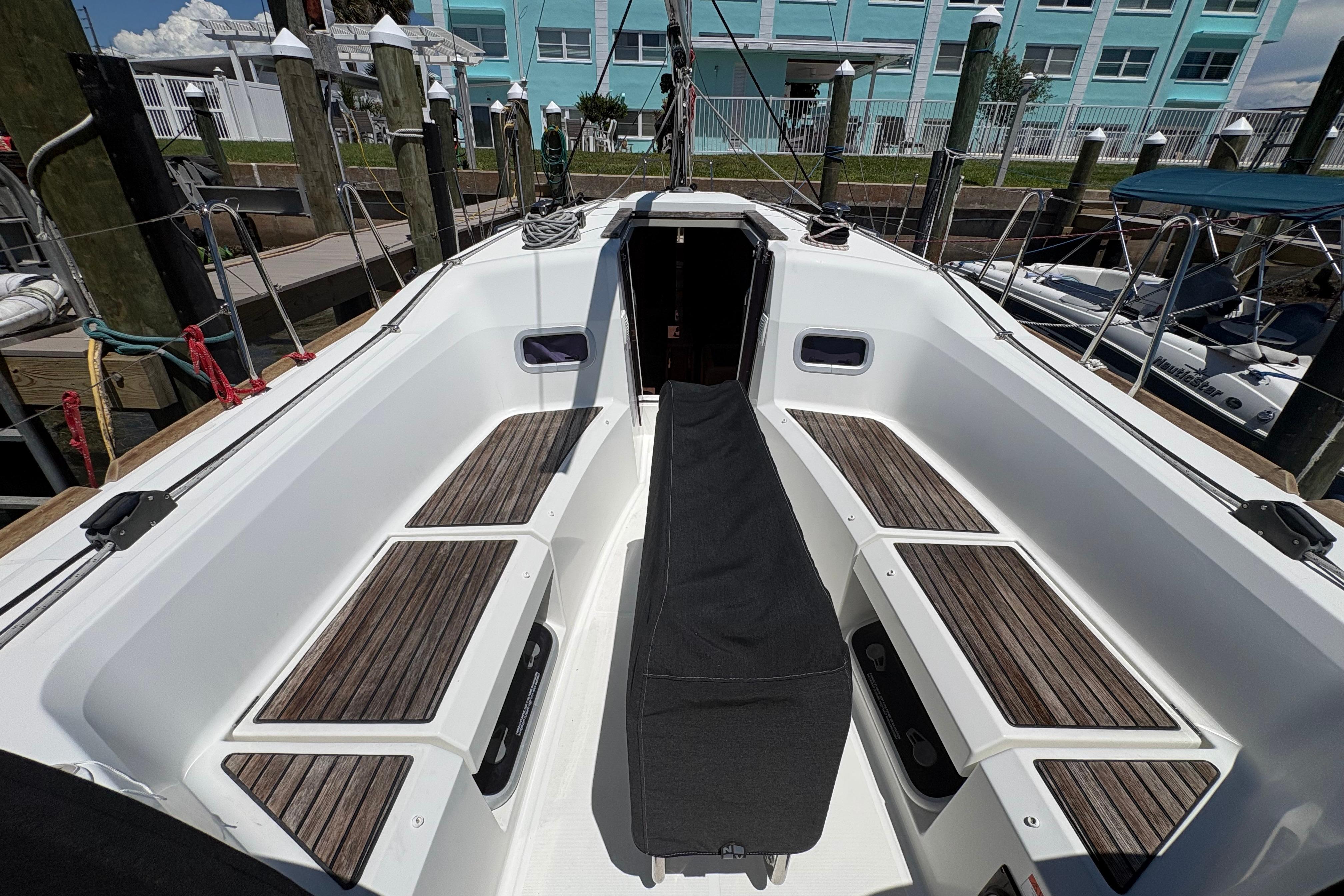 Cockpit of 2021 Jeanneau Sun Odyssey 349 sailboat with wooden seating and covered helm.