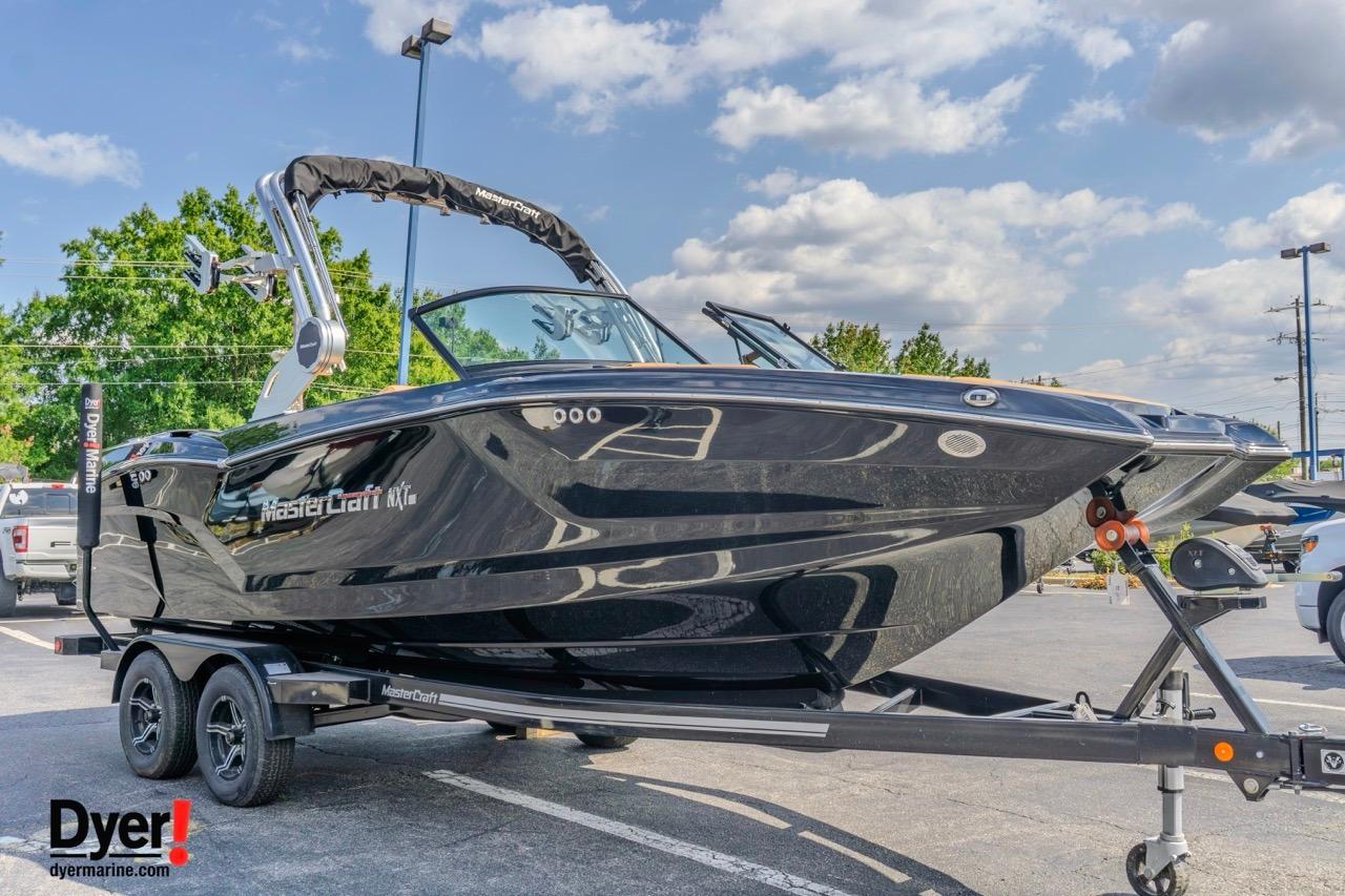 2026 MasterCraft NXT22 boat on trailer, sleek black design, parked outdoors.