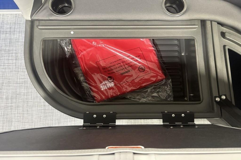 Storage compartment in 2026 Sun Tracker Party Barge 16 DLX with red life jacket.