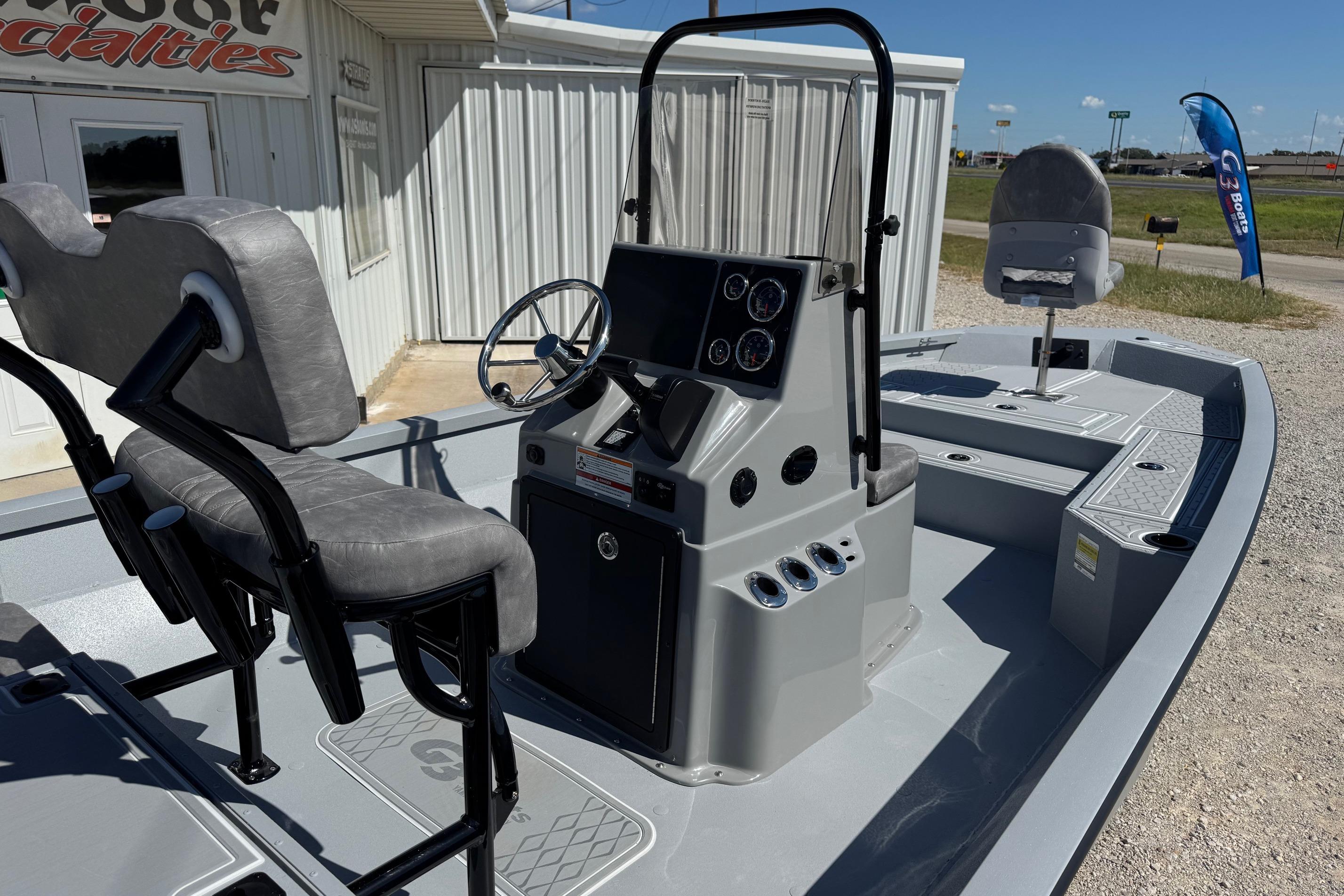 2026 G3 21GX boat interior with steering console and seating, parked outside a building.