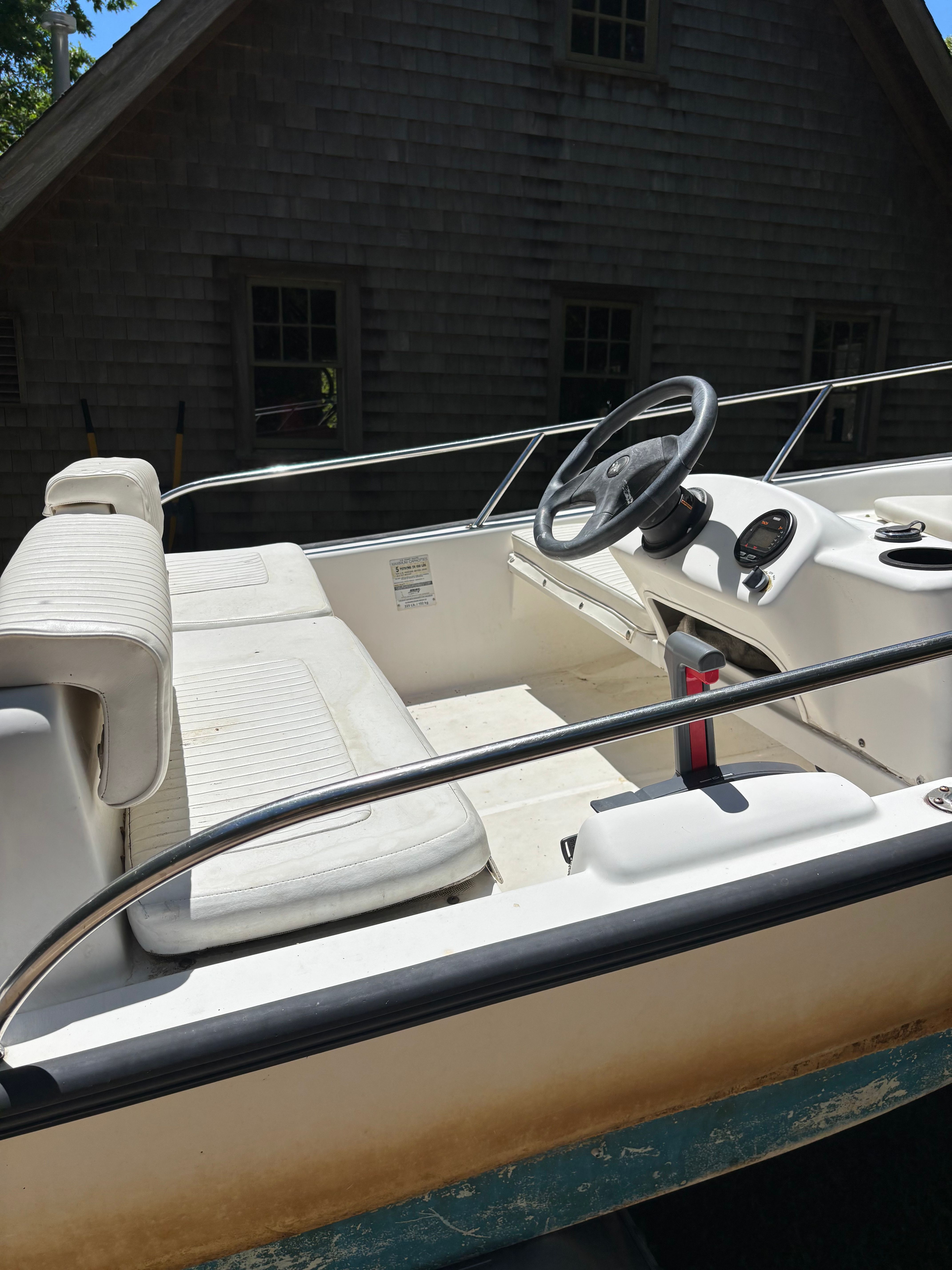Interior view of a Boston Whaler 130 Sport with white seats and steering wheel.