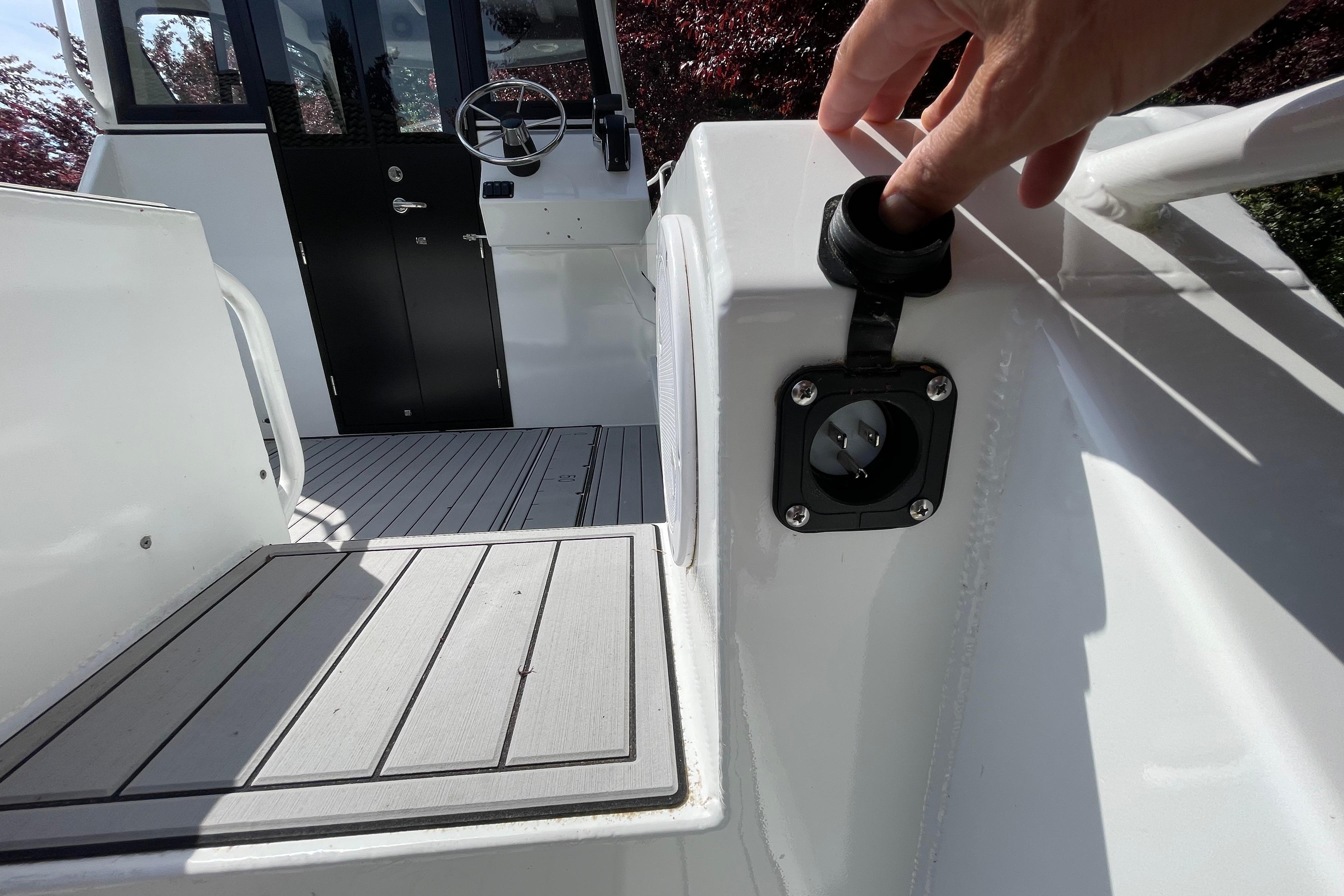 2025 Custom Aluminum 7.5 Profisher boat deck with hand touching power socket.