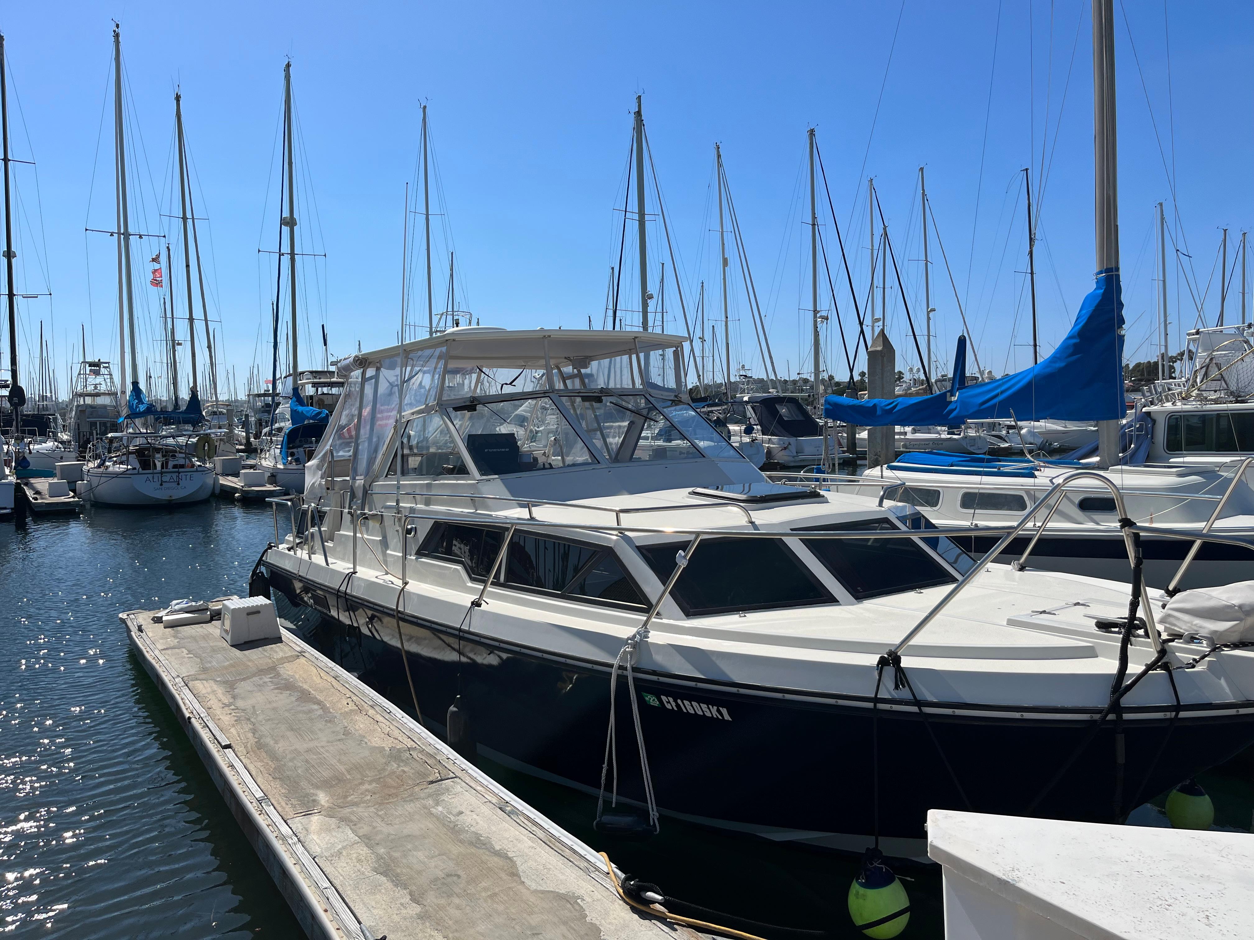 1987 Scand Baltic boat docked at a marina with sailboats in the background.