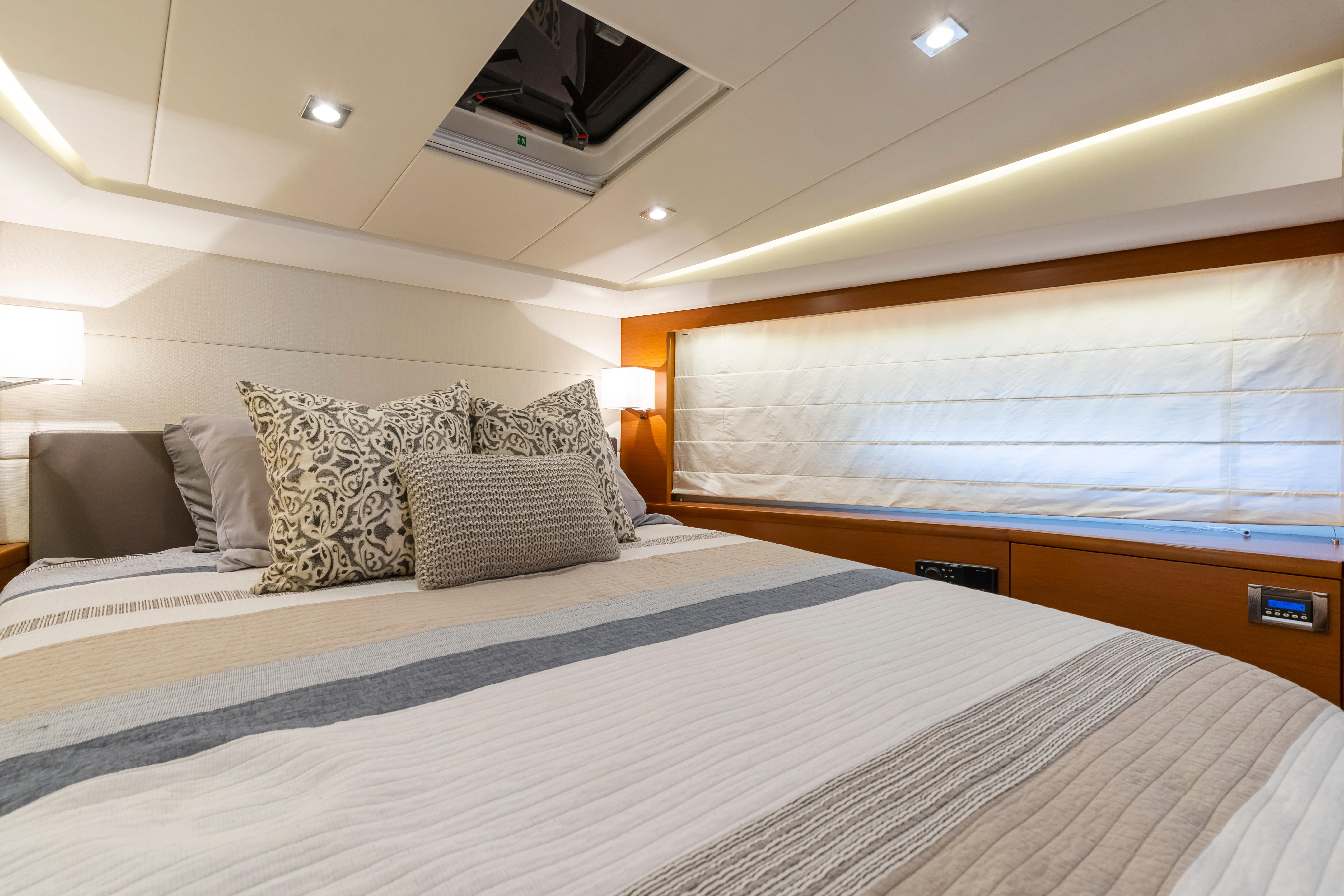 Luxurious bedroom interior of 2017 Prestige 500 yacht with elegant bedding and ambient lighting.
