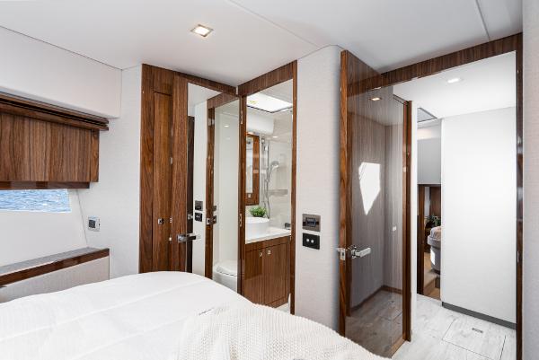 Luxurious interior of 2021 Riviera 5400 Sport Yacht master bedroom and ensuite bathroom.