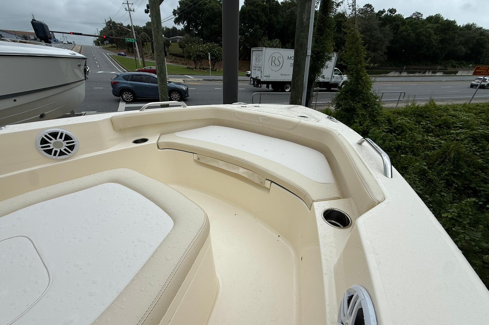 2027 Scout 188 Sportfish boat interior with seating and cup holders, parked near a road.
