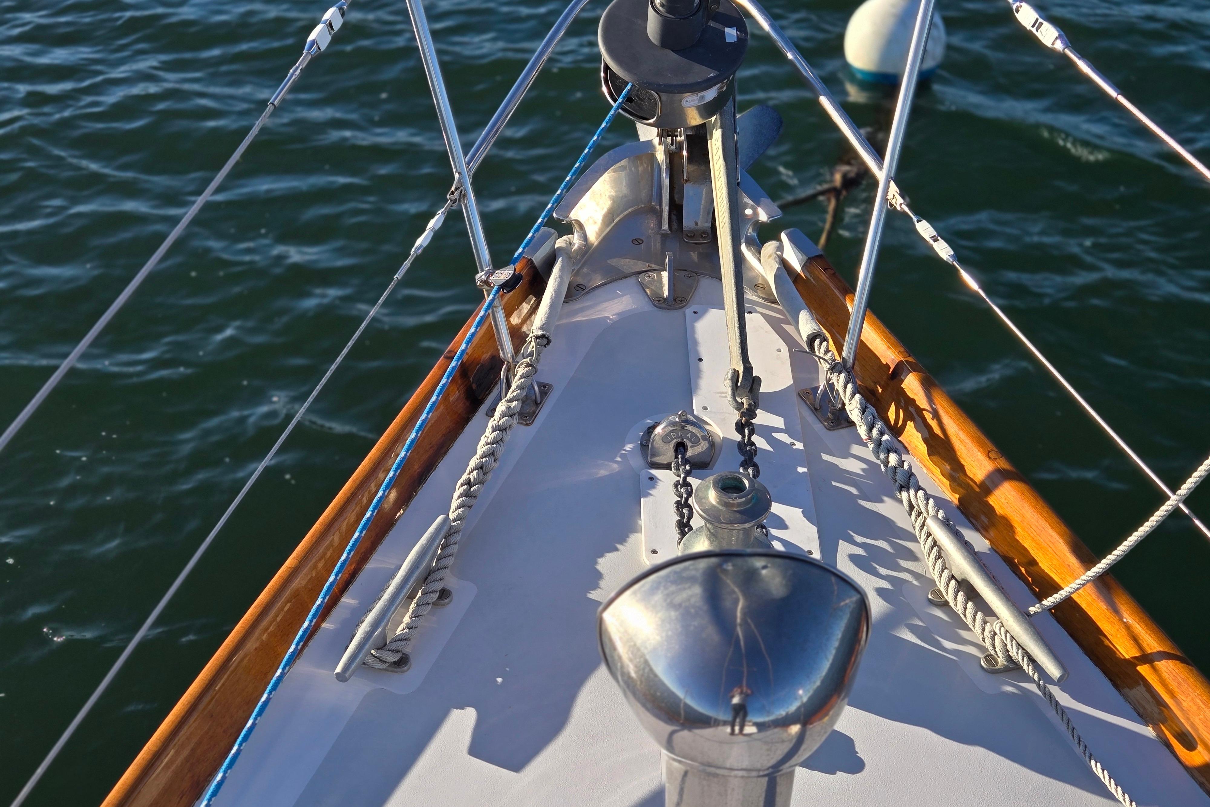 Bow of a 1970 Hinckley Bermuda 40 sailboat with ropes and winch on deck.