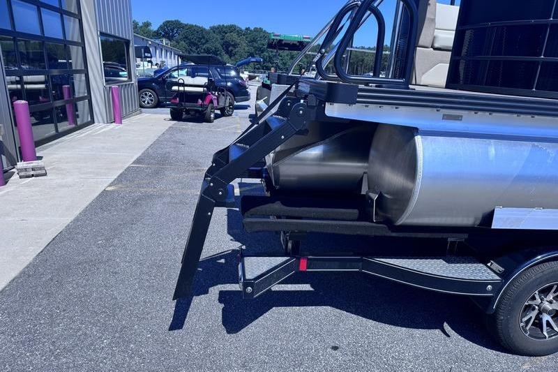 2027 Manitou Aurora 23 RF SHP pontoon boat on trailer in parking lot.