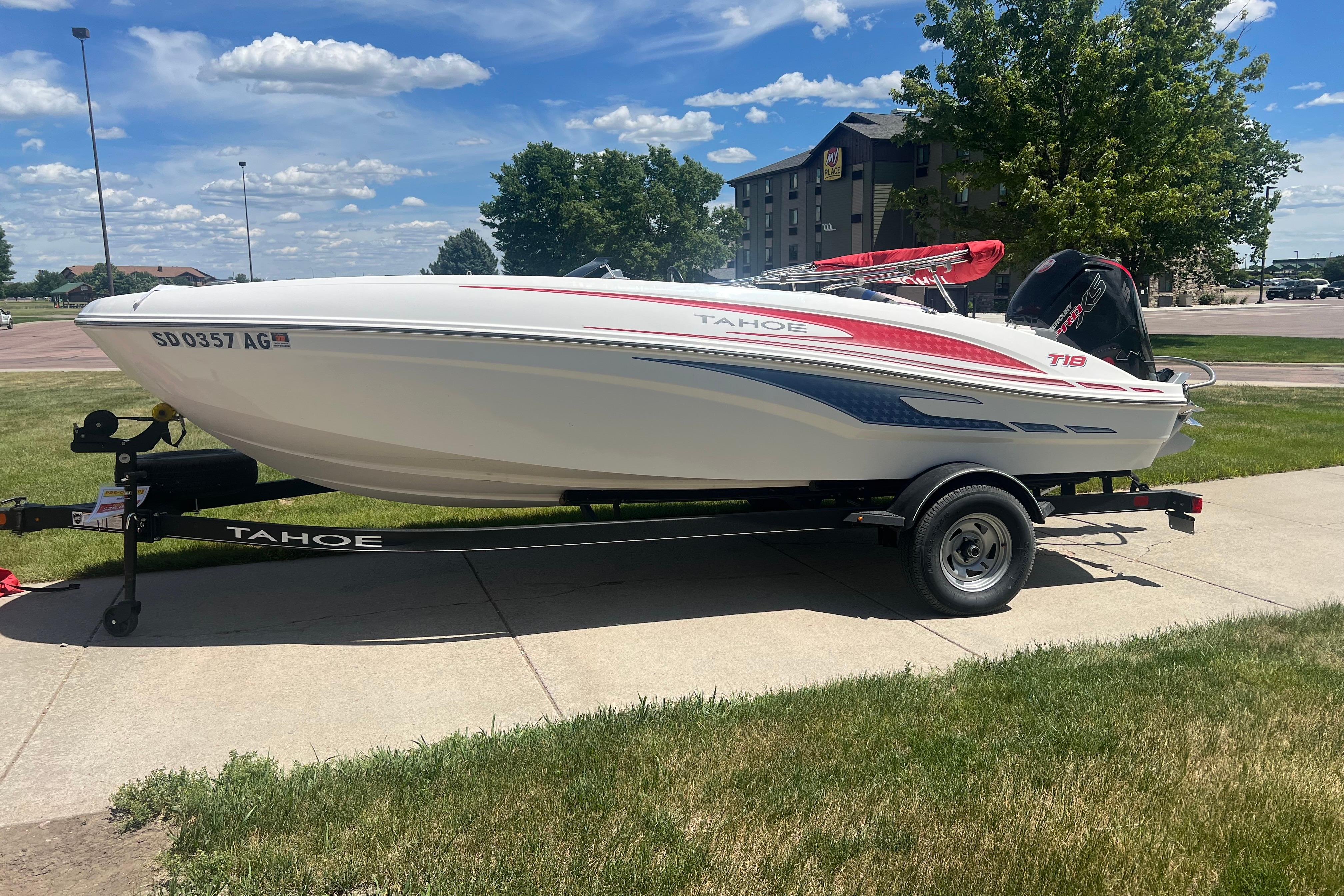 2023 Tahoe T18 boat on trailer, parked on grass under a clear blue sky.