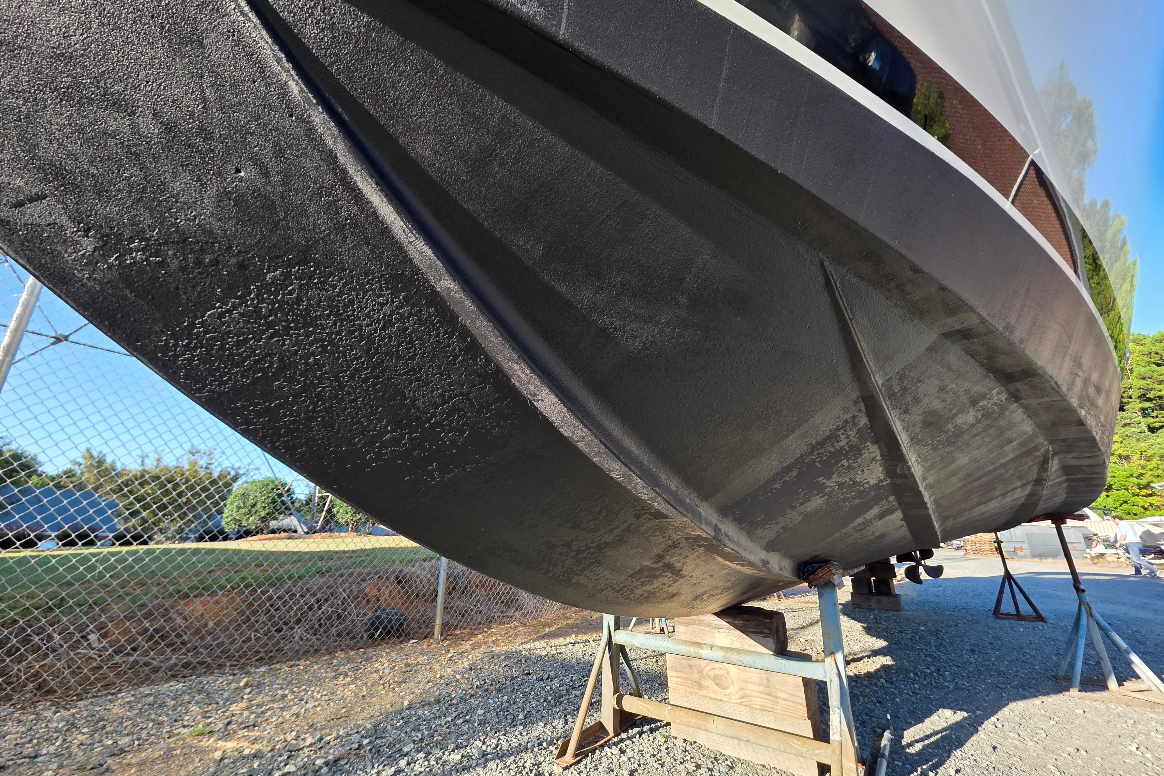 1998 Maxum 3700 SCR boat hull on stands, outdoor storage area.