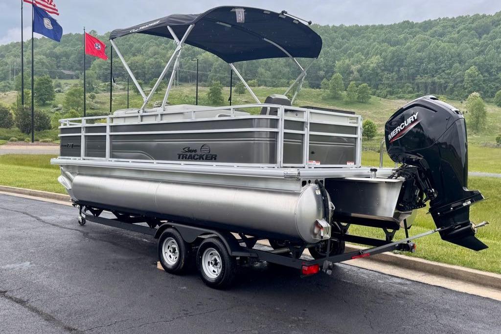 2026 Sun Tracker Fishin' Barge 20 DLX pontoon boat on trailer, parked outdoors.