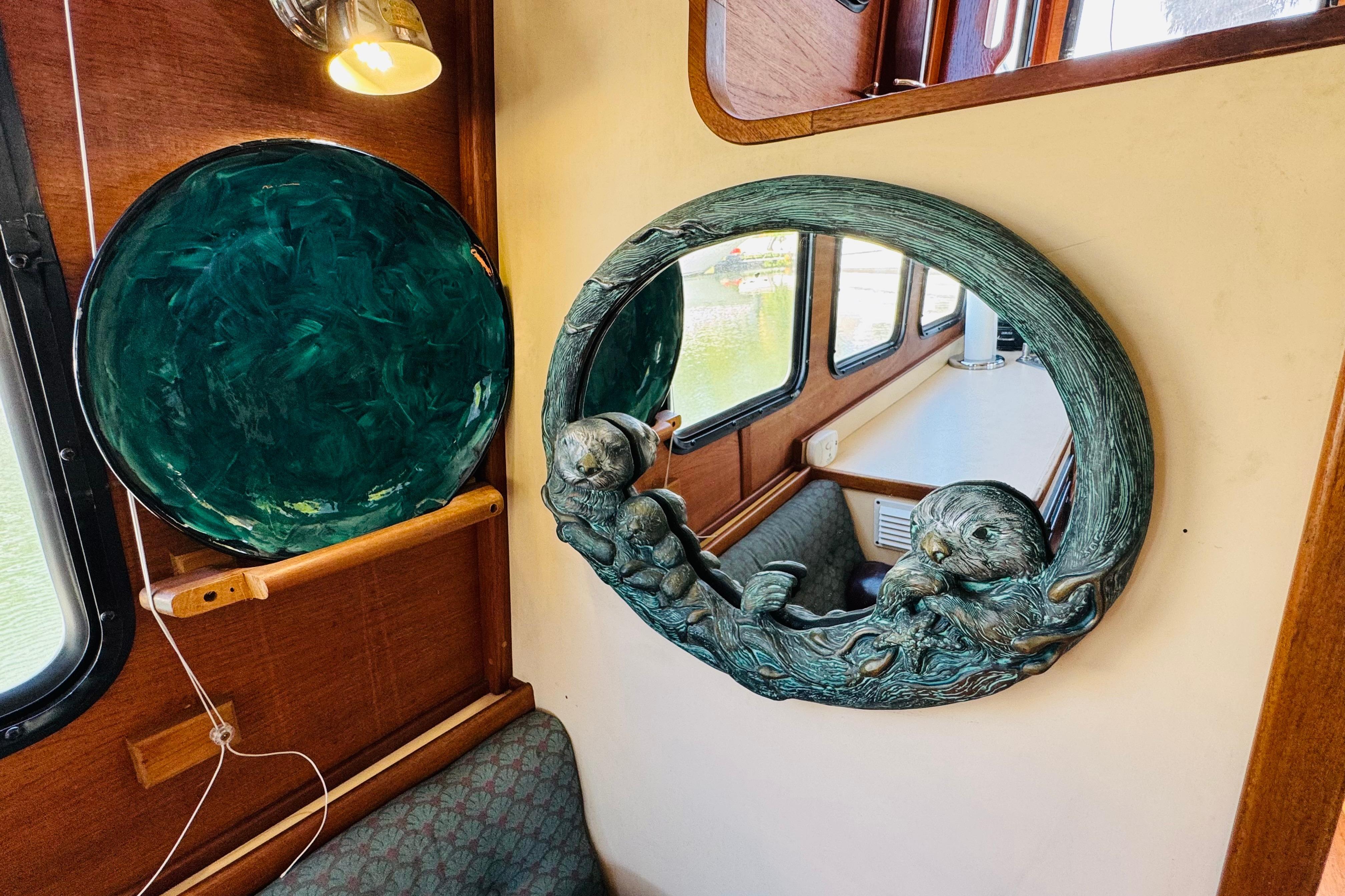 Interior of 1996 Nordic Tug 32 with decorative mirror and green plate on wooden wall.