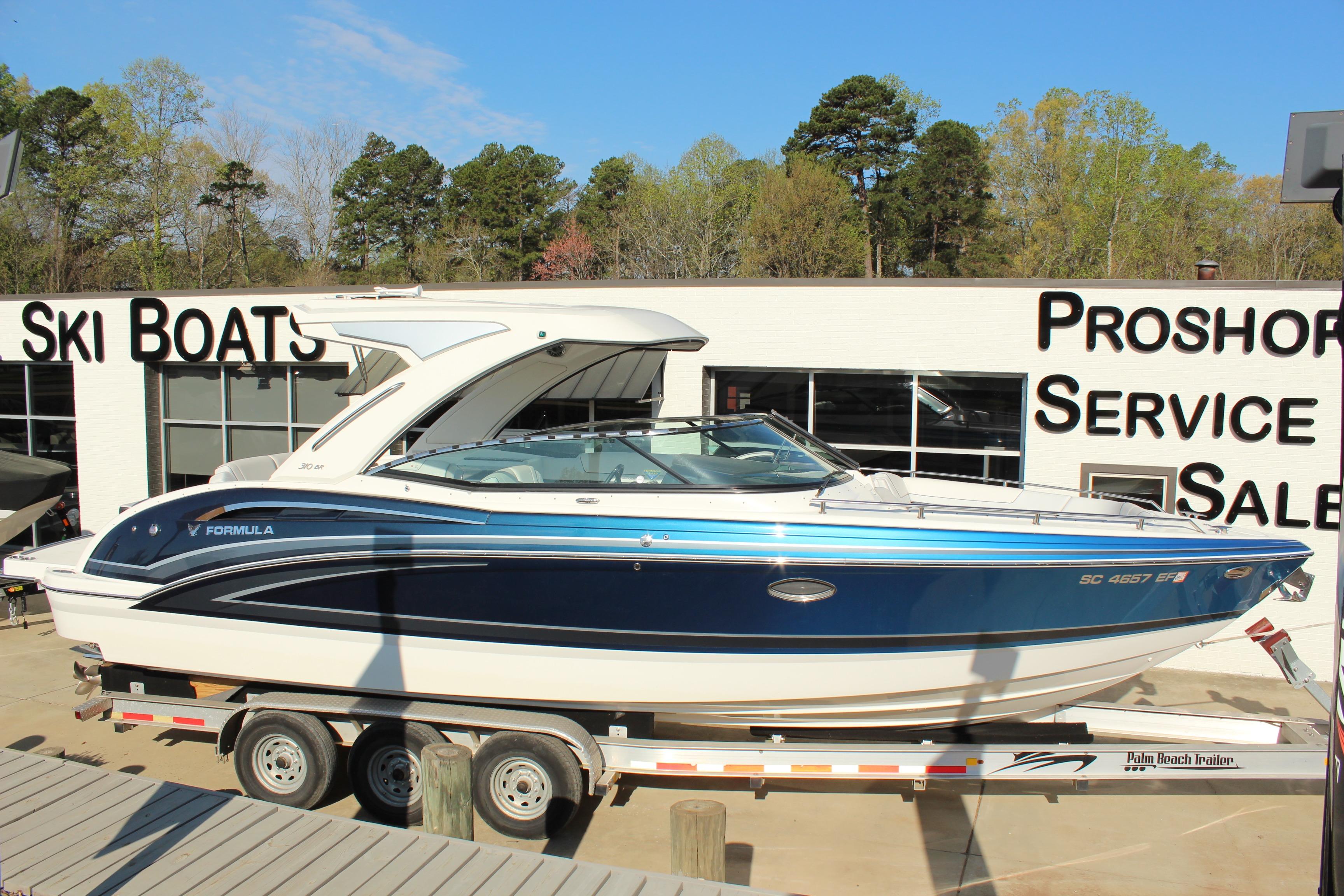 2023 Formula 310 Bowrider I/O boat on trailer at dealership, sunny day.