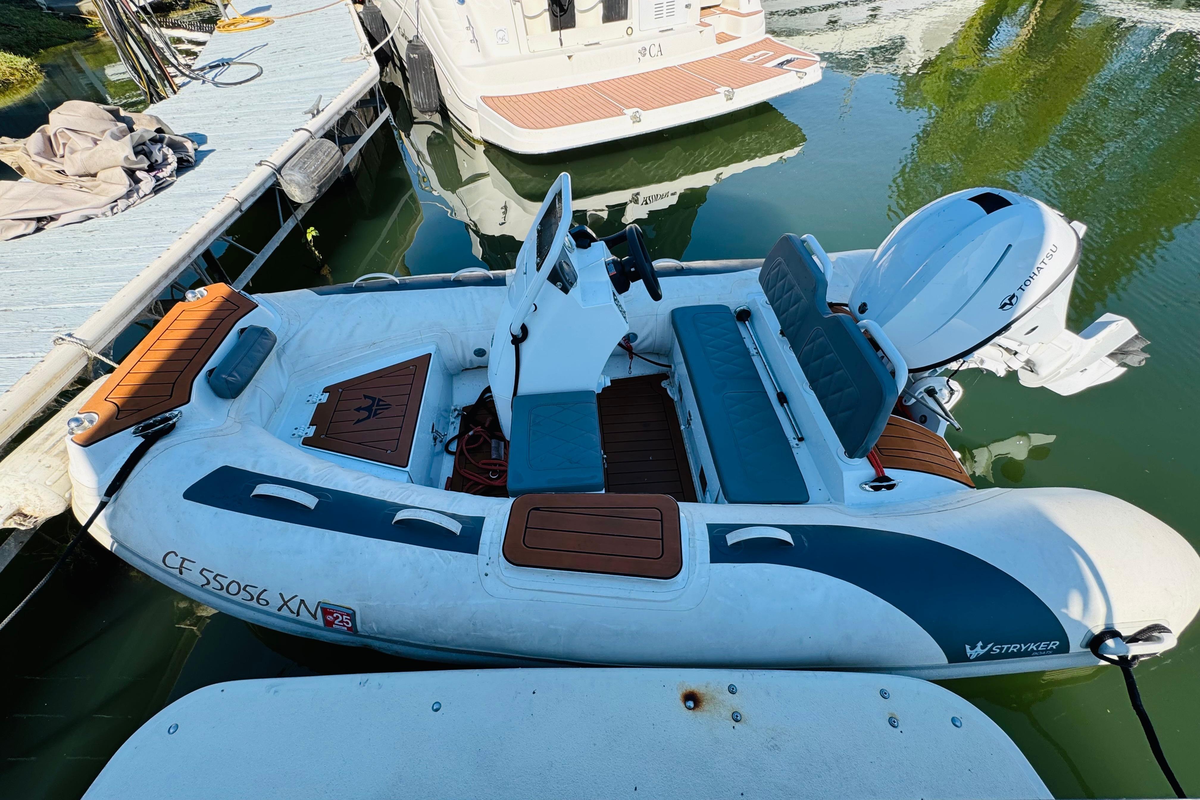 A 1996 Nordic Tug 32 docked, featuring a Stryker inflatable boat with Tohatsu outboard motor.
