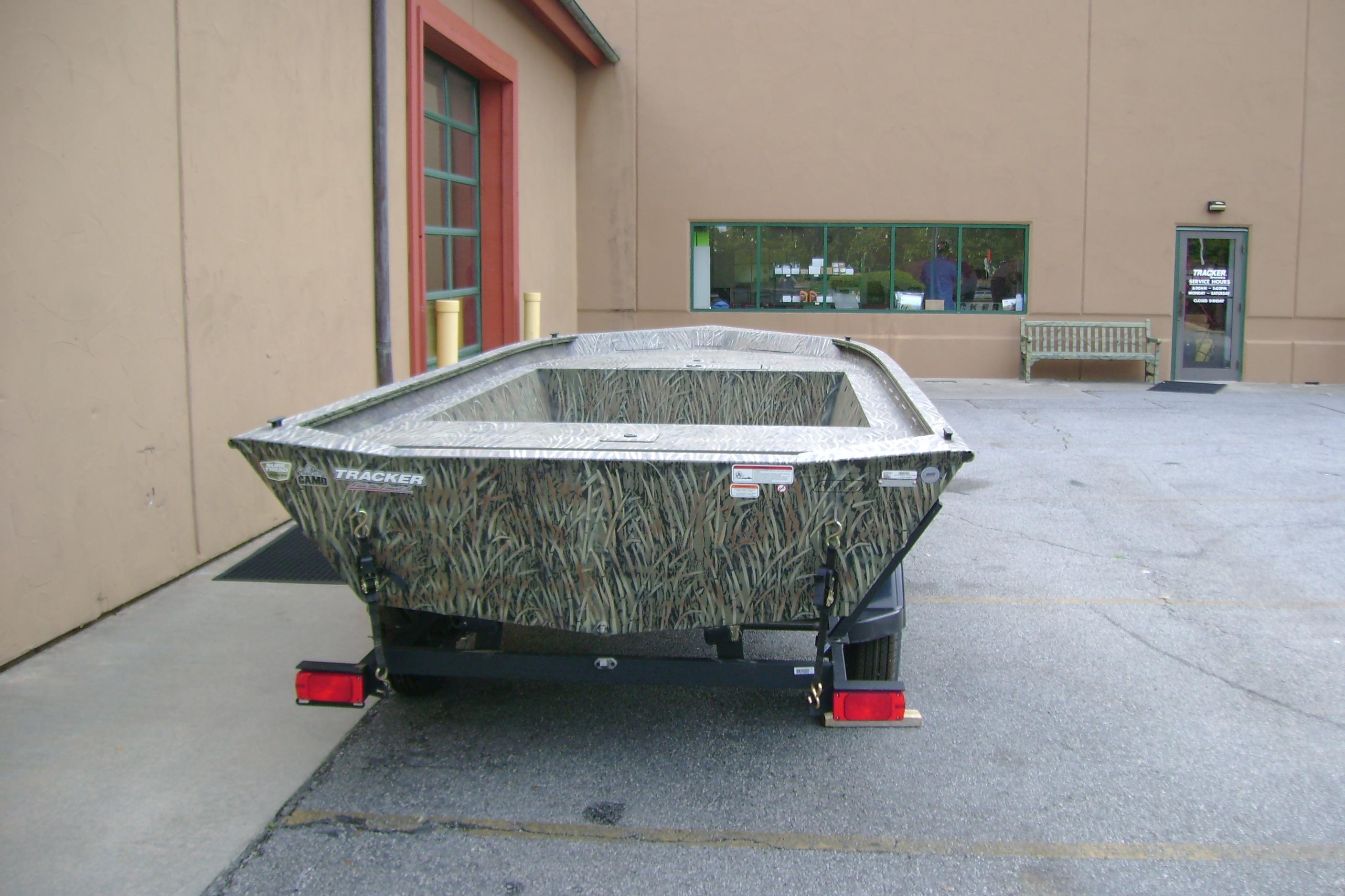 2026 Tracker Grizzly 1754 Utility boat with camouflage design parked outside a building.