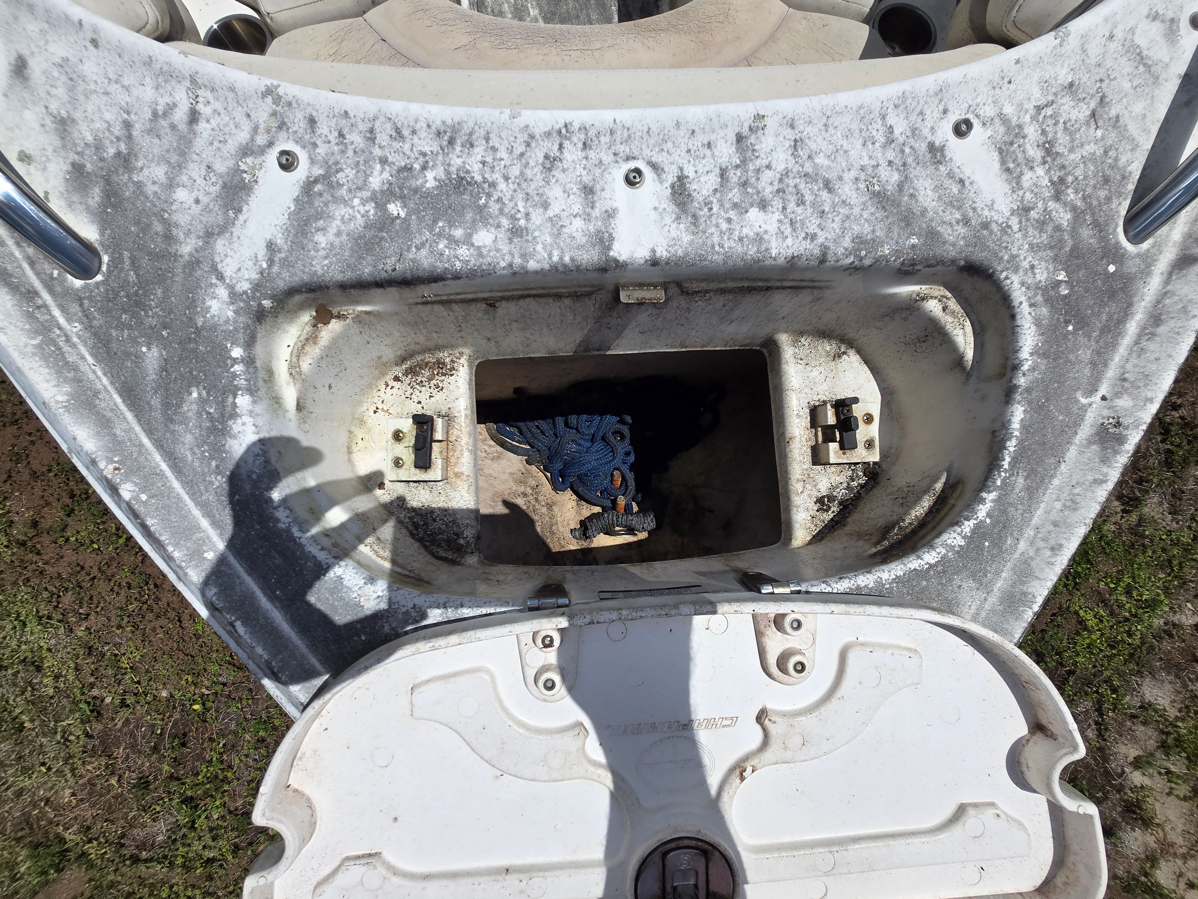 An open storage compartment on a boat with a rope inside.