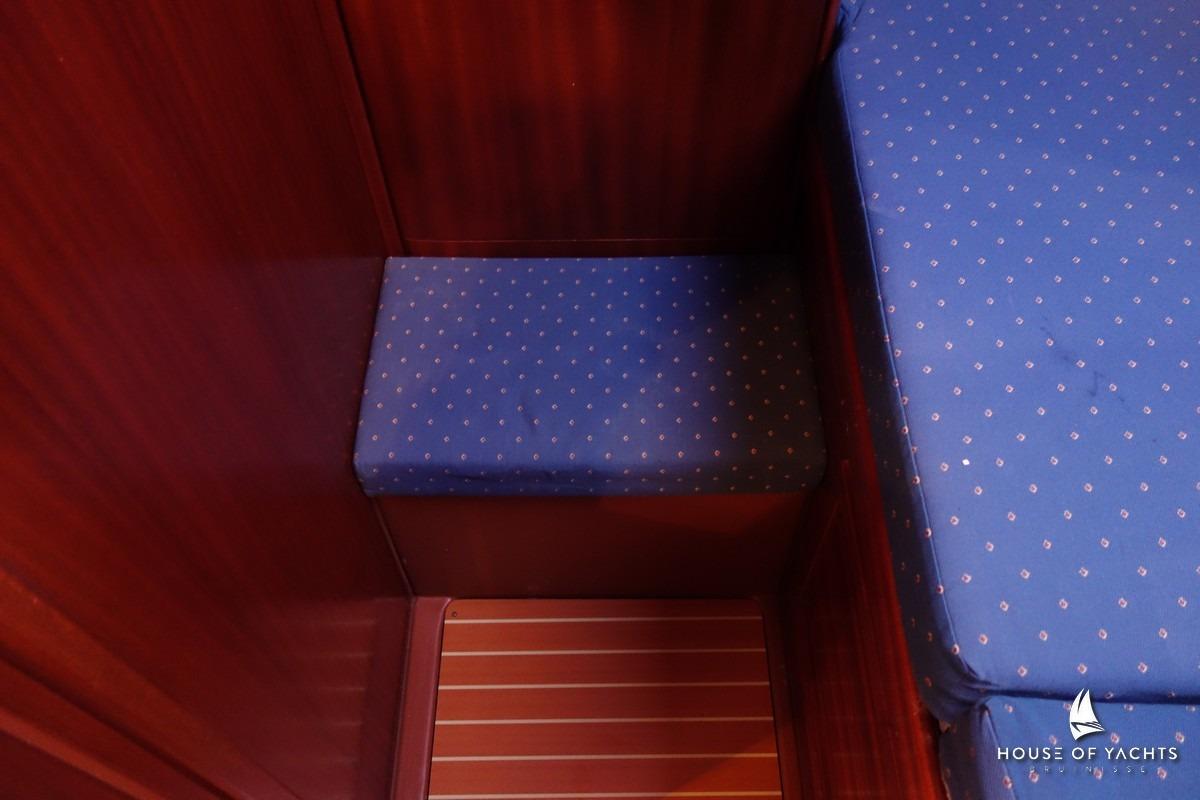 Interior of 2003 Bavaria 32 yacht with blue cushioned seating and wooden paneling.