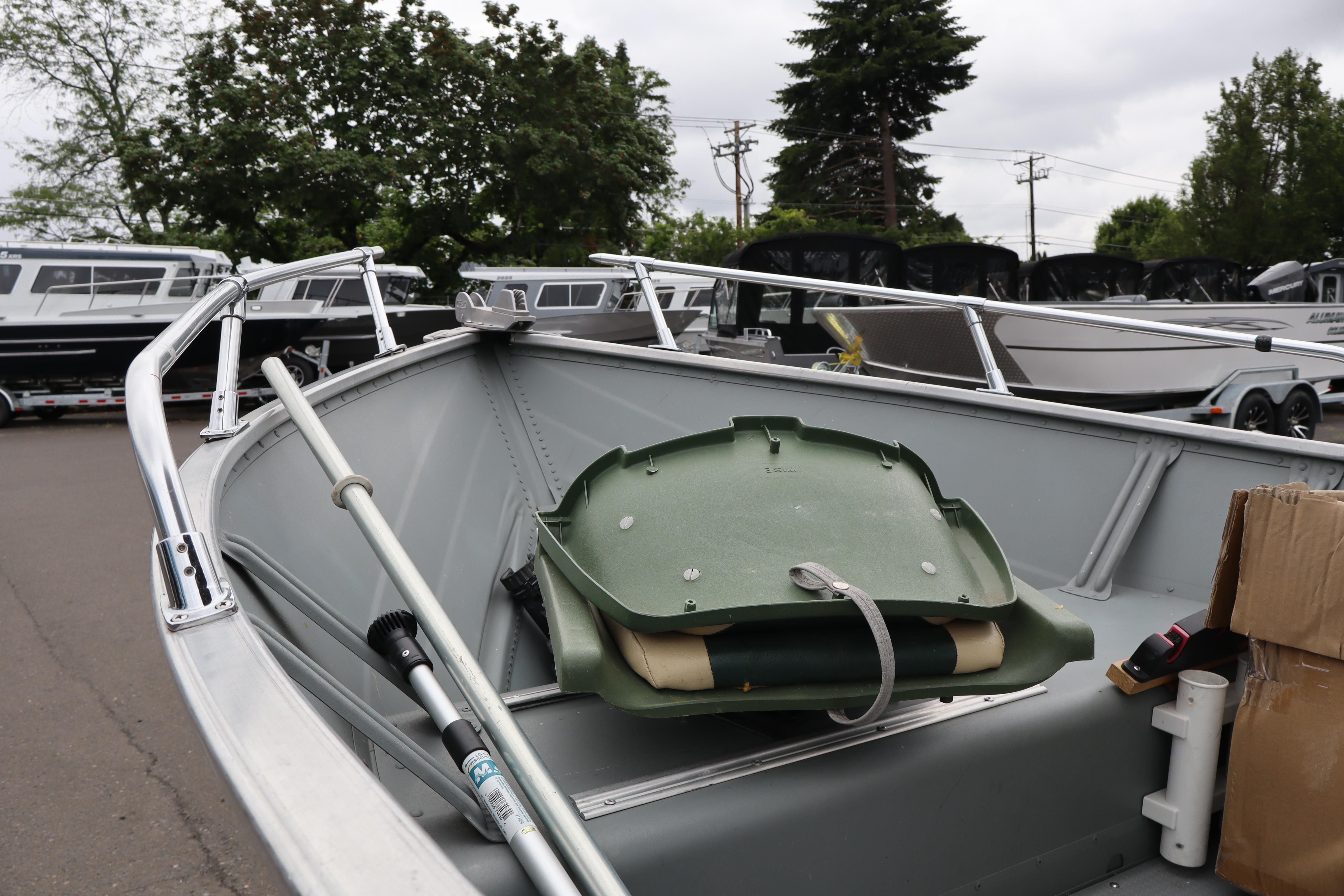2006 Smoker Craft Alaskan 15 boat with oars and equipment, parked outdoors.