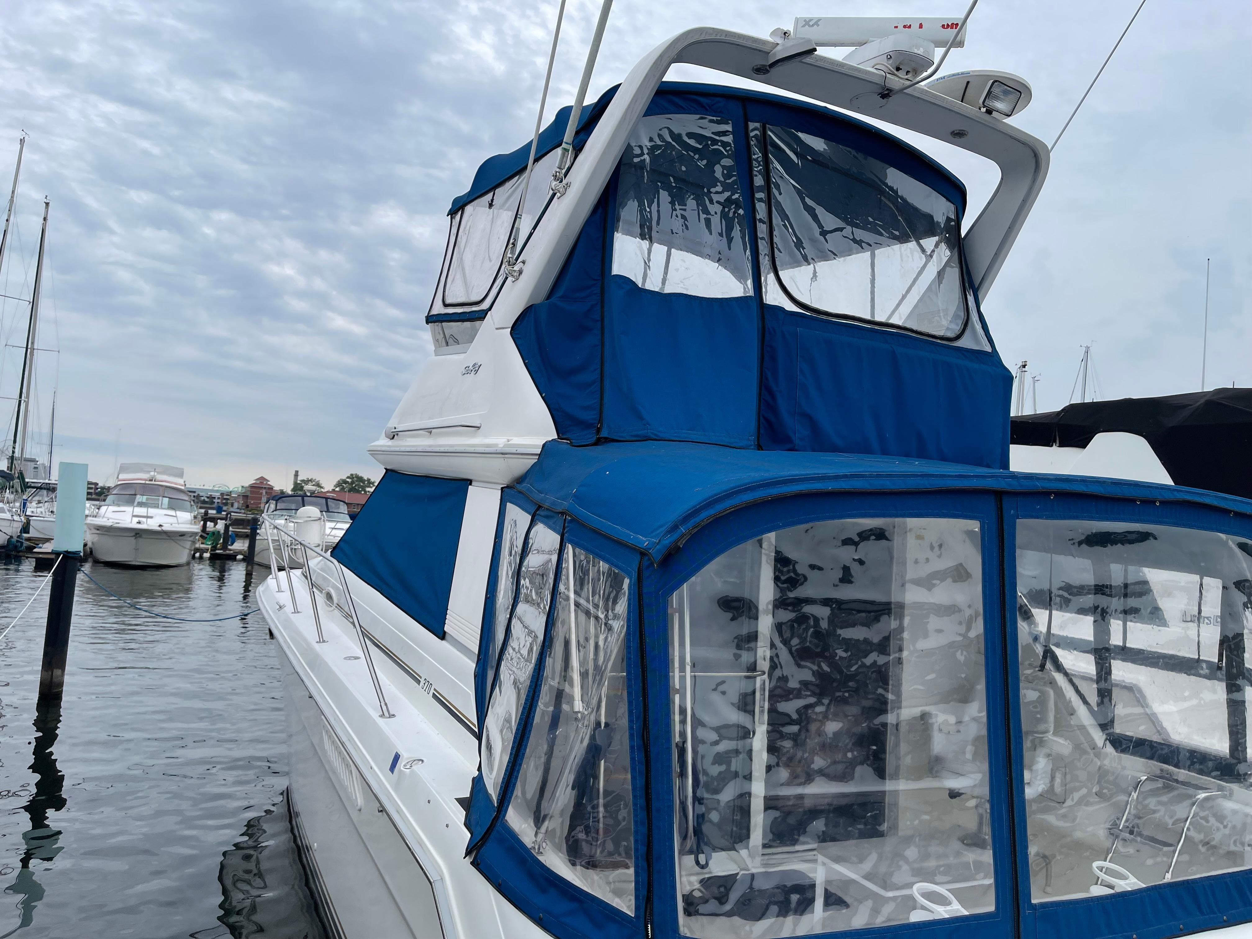 A 1996 Sea Ray 370 Sedan Bridge with blue covers, docked in a marina.