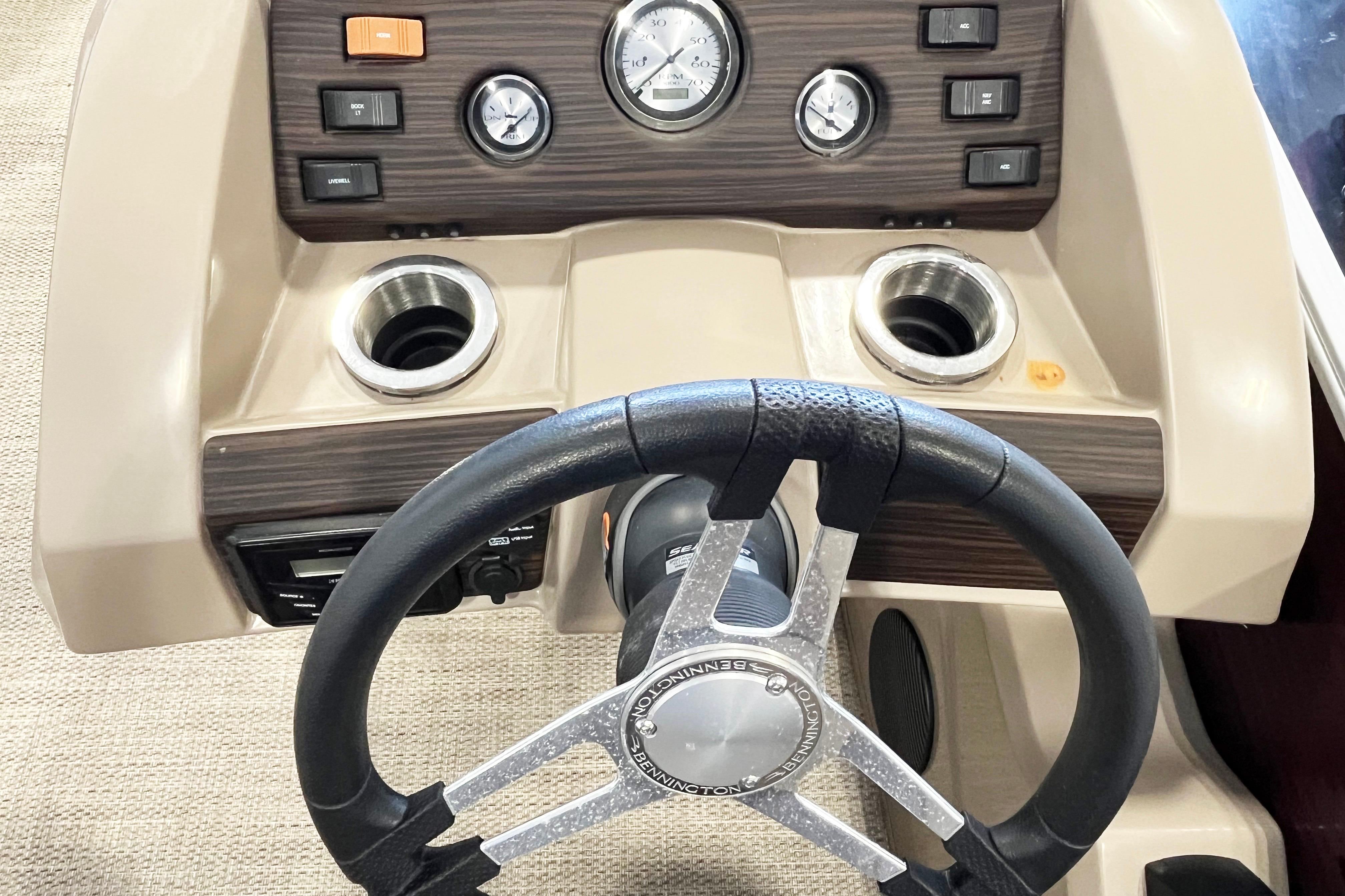 Steering wheel and dashboard of 2020 Bennington SX25 boat with controls and cup holders.
