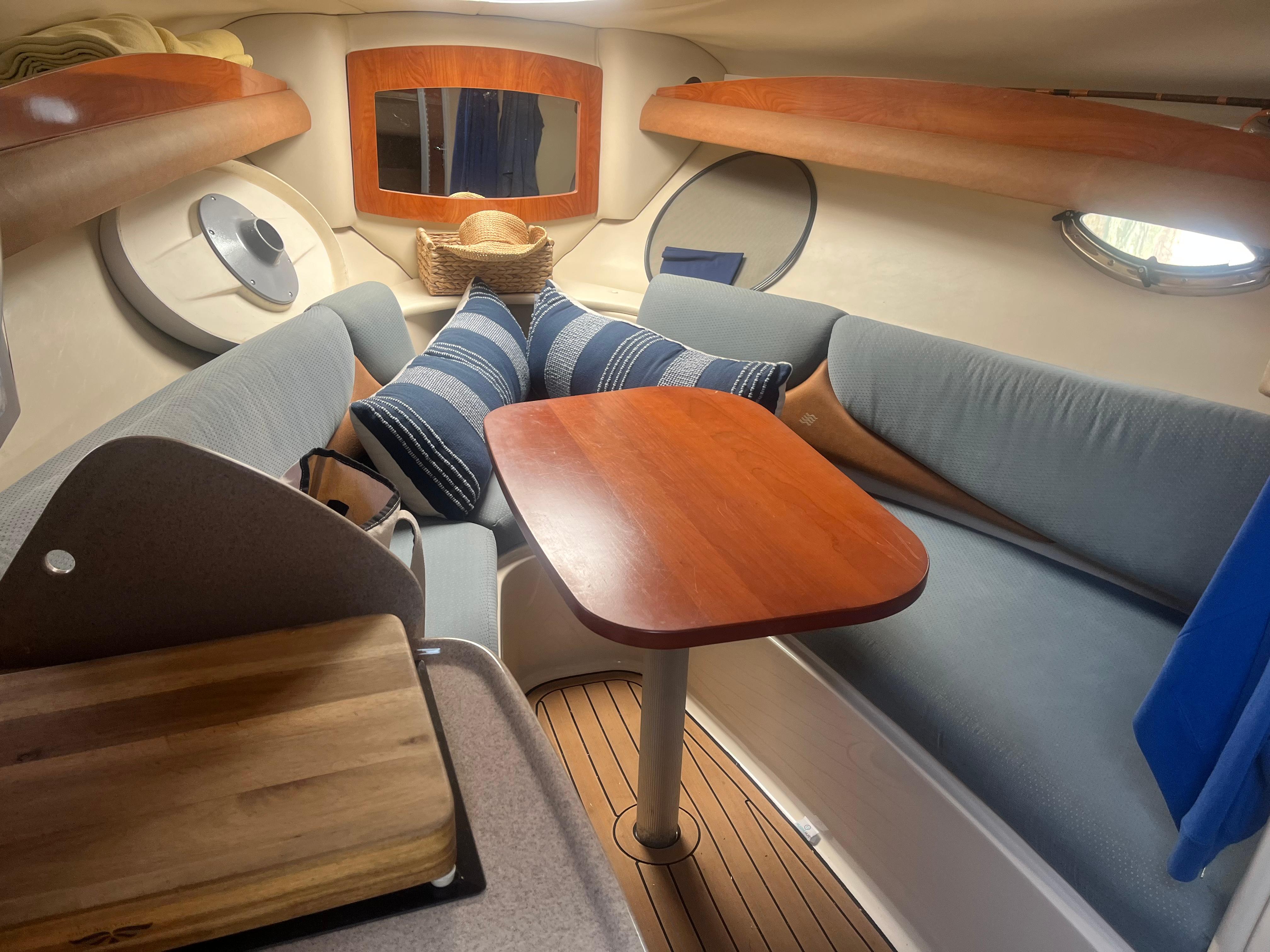 2007 Four Winns 258 Vista cabin interior with cozy seating and wooden table.