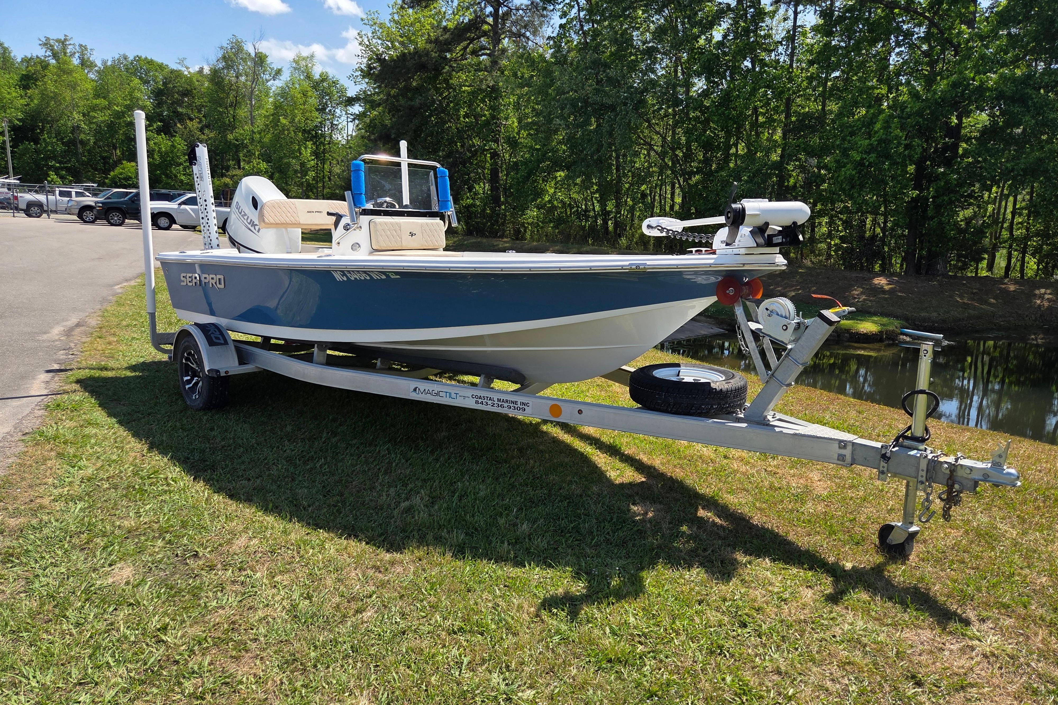 2024 Sea Pro 172 Bay boat on trailer, parked on grass near a pond.