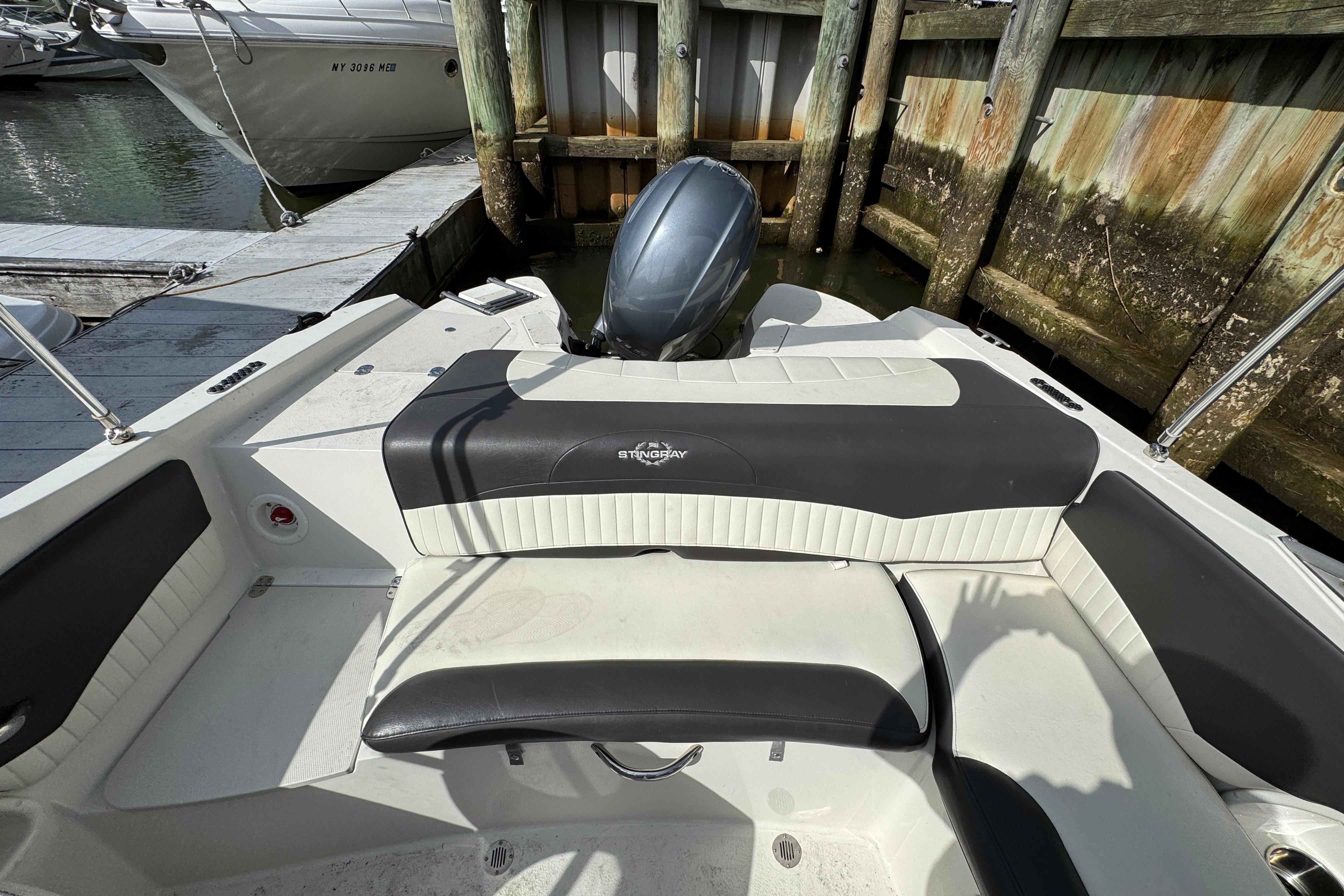 2019 Stingray 204 LR boat interior with seating and motor, docked by wooden pier.